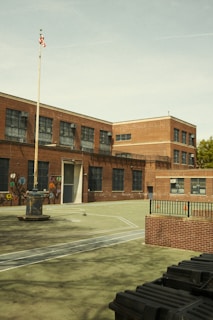 An old brick school building with a flagpole stands.