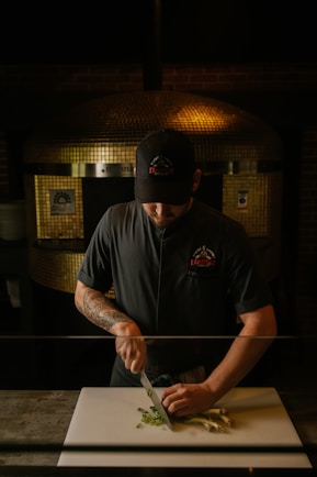 A chef prepares vegetables for a pizza.