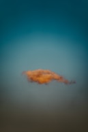 A single, orange cloud floats in the sky.