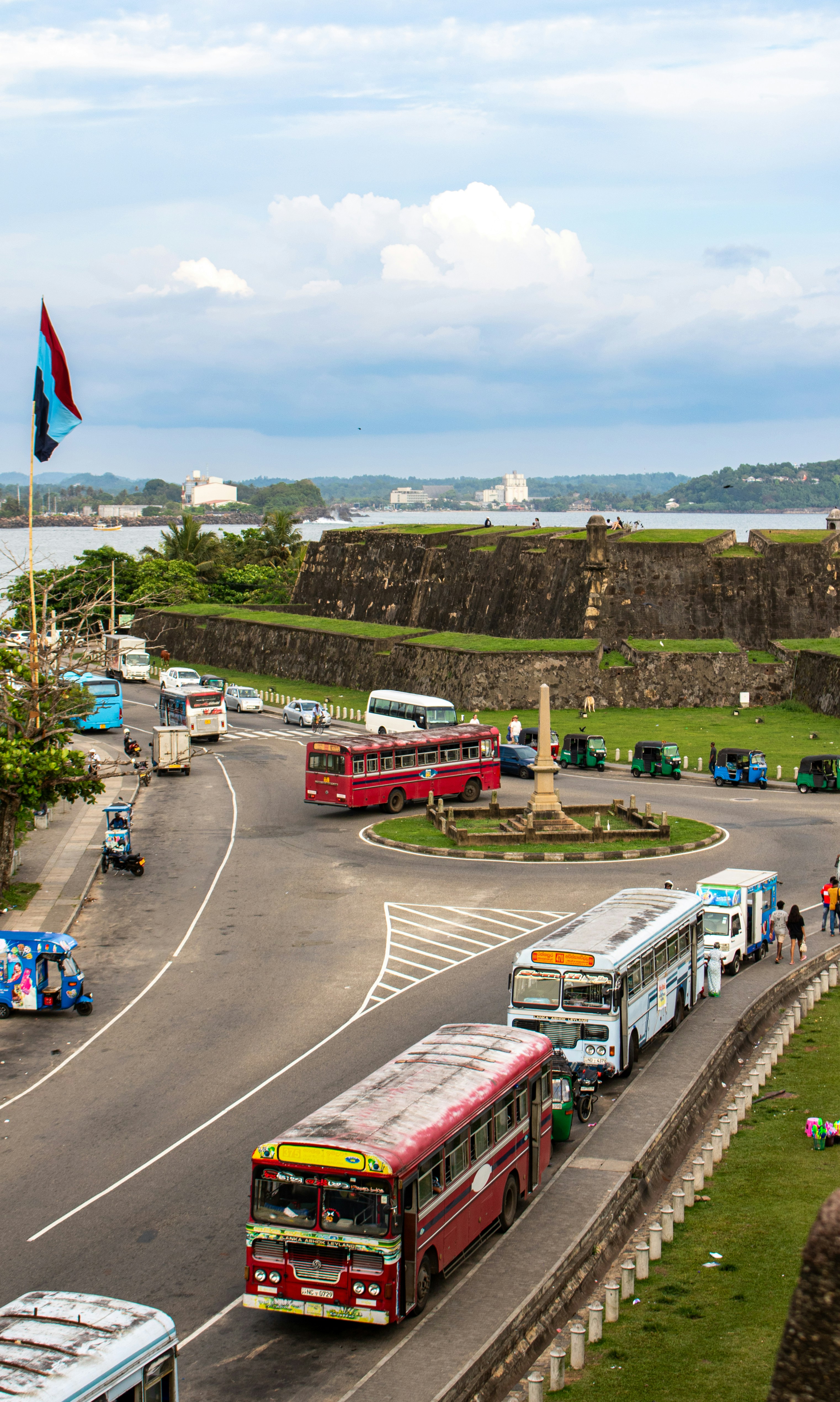 Buses and traffic near a fort by the ocean.