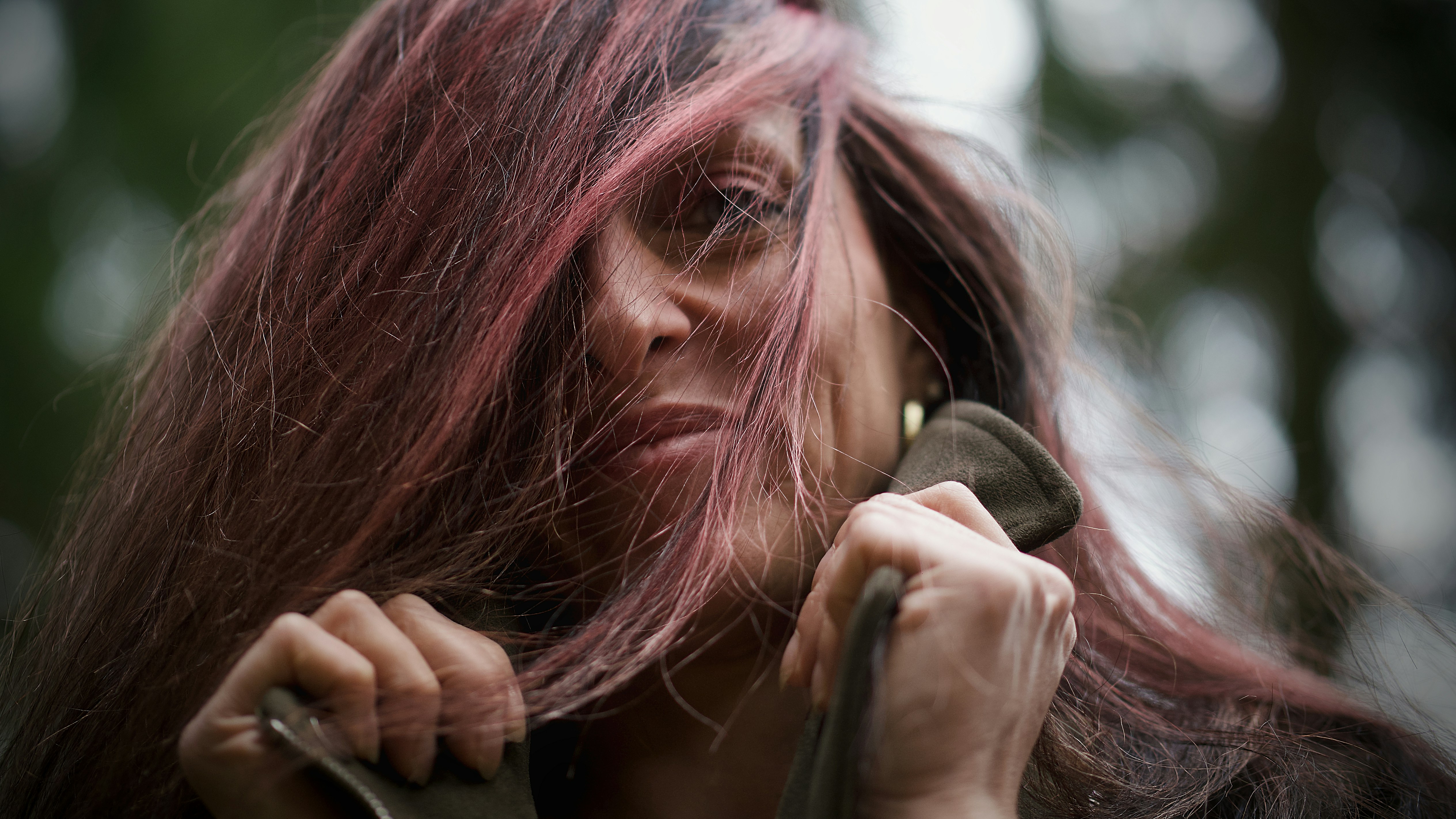 Woman with pink hair pulling up a jacket.