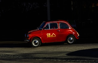 A red classic car parks on the road.
