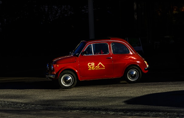 A red classic car parks on the road.