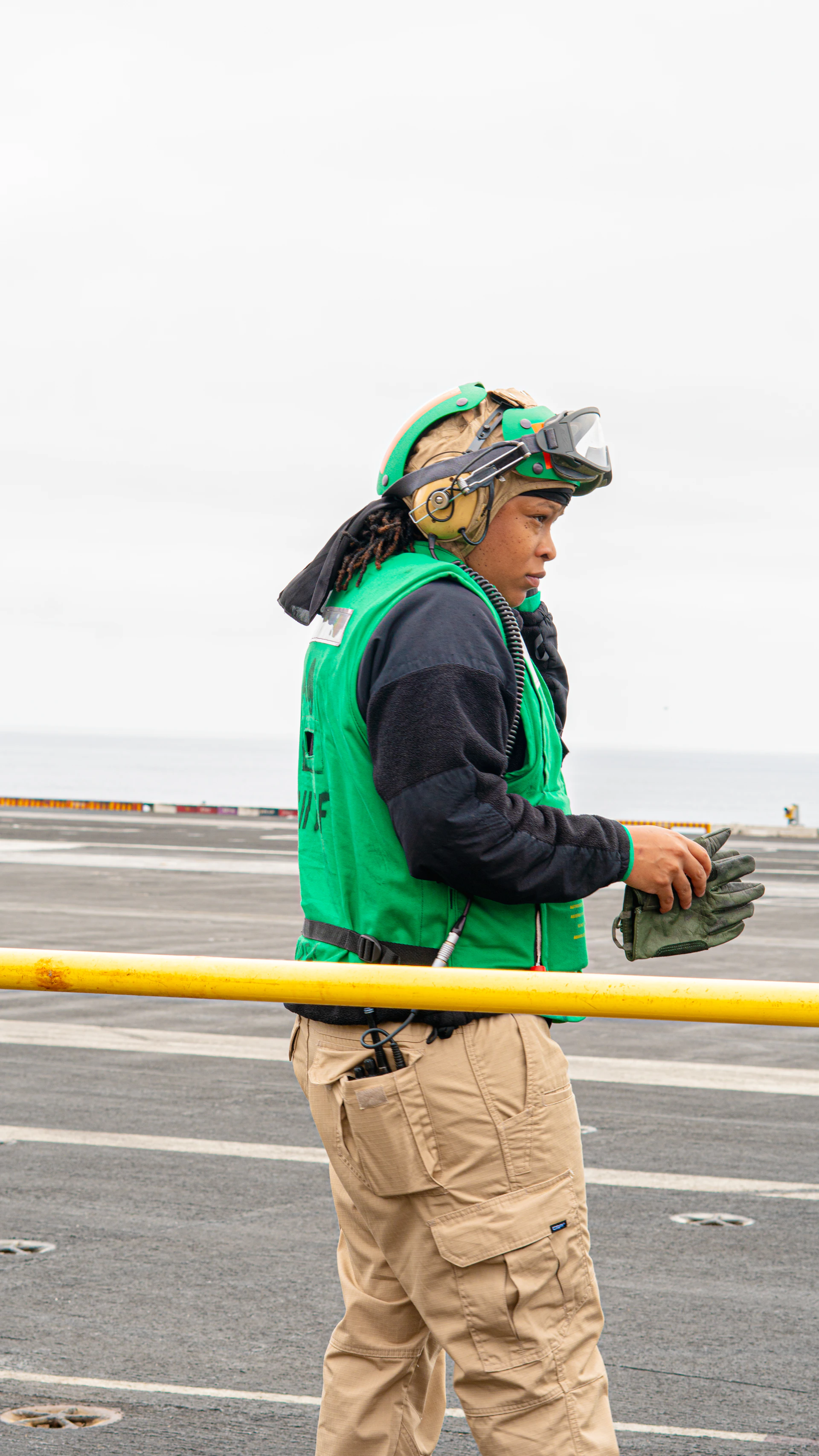 A person in uniform stands on an aircraft carrier.