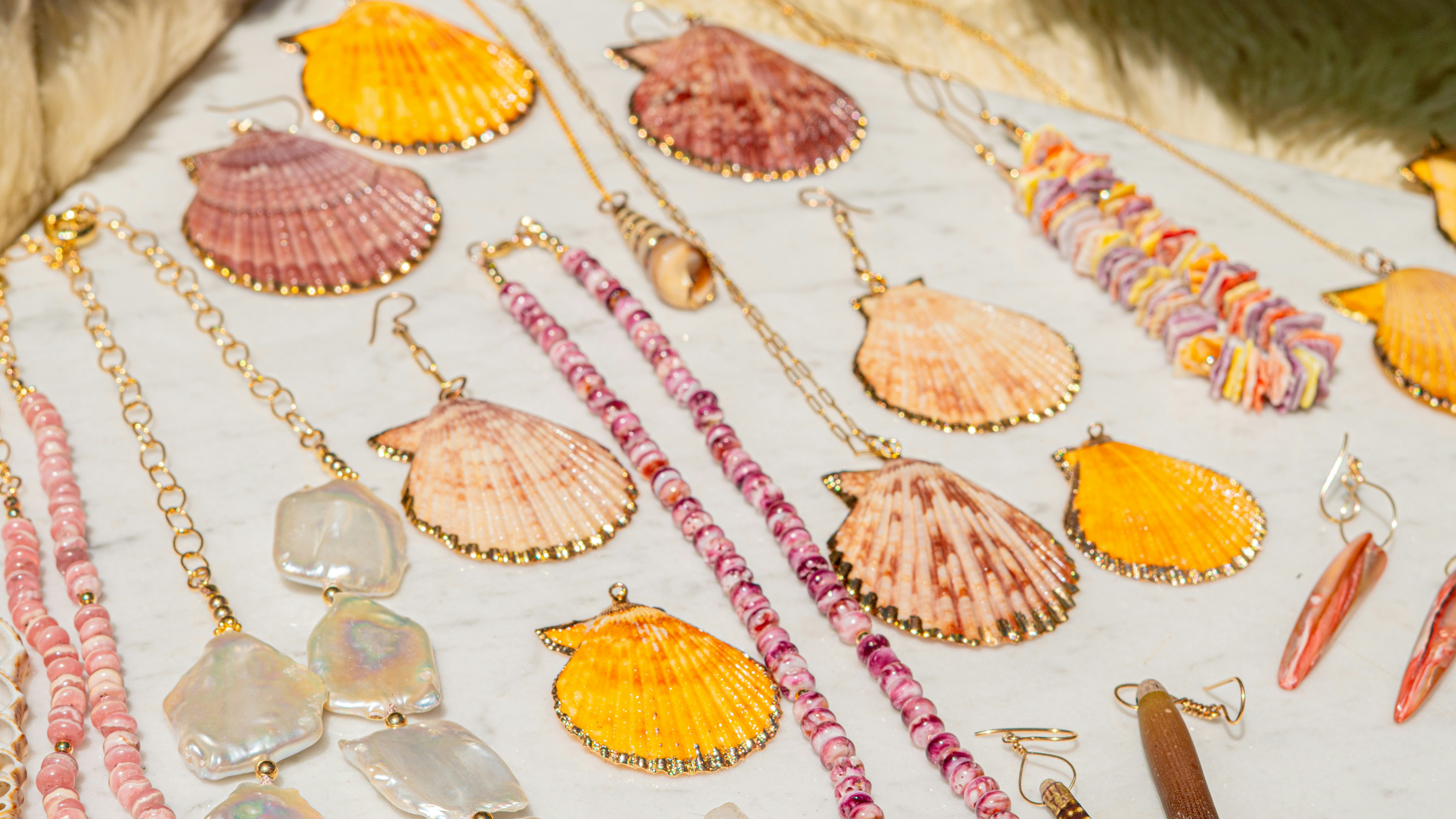 Seashell jewelry pieces arranged on a white surface