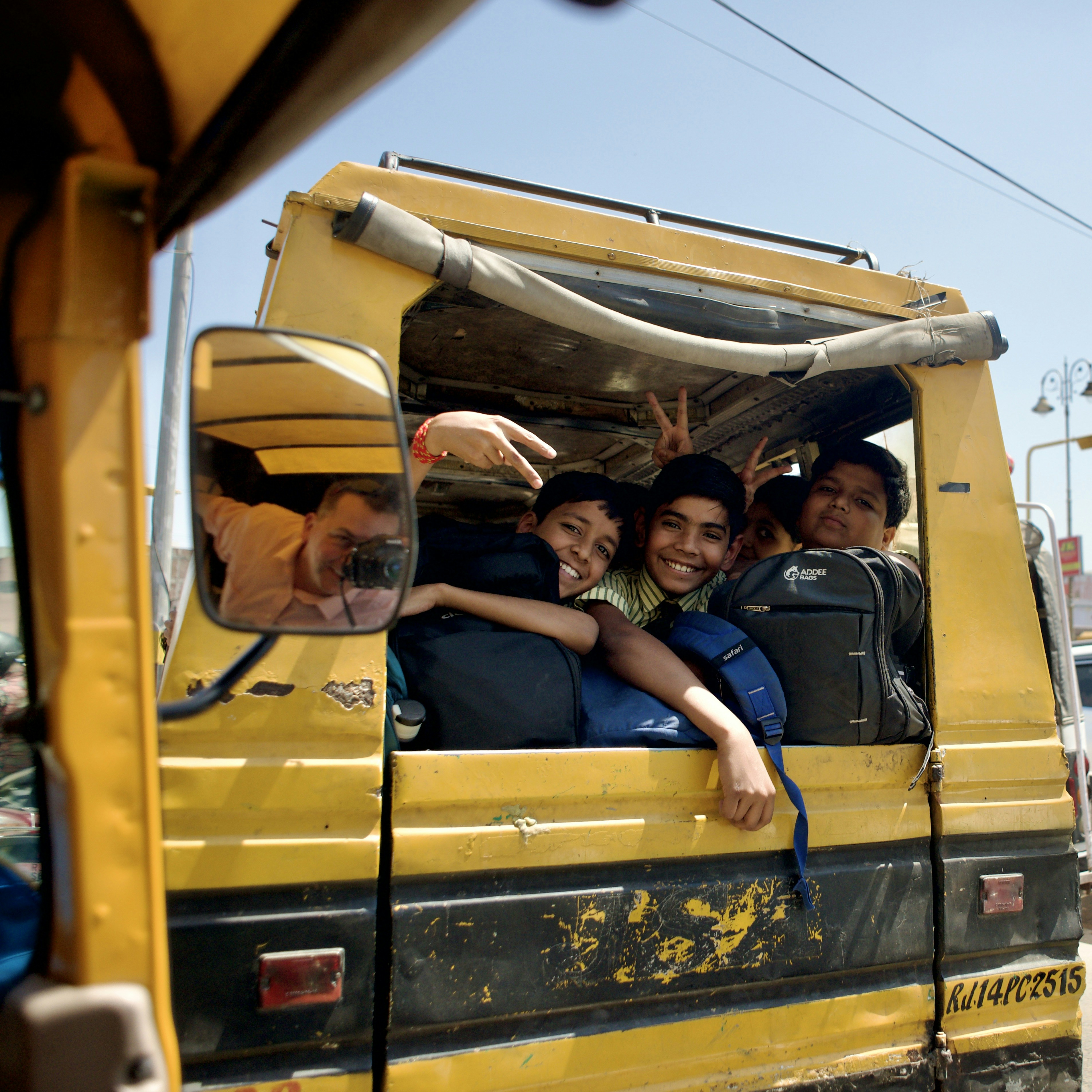 Happy kids ride in a yellow auto-rickshaw.