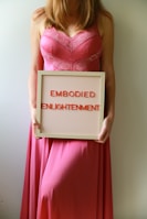 Woman holds sign that reads "embodied enlightenment".