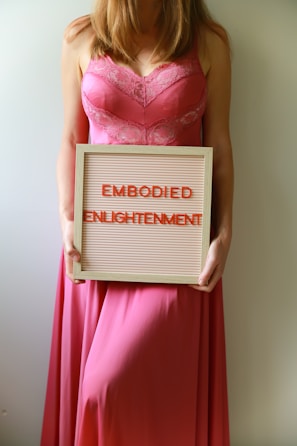 Woman holds sign that reads "embodied enlightenment".
