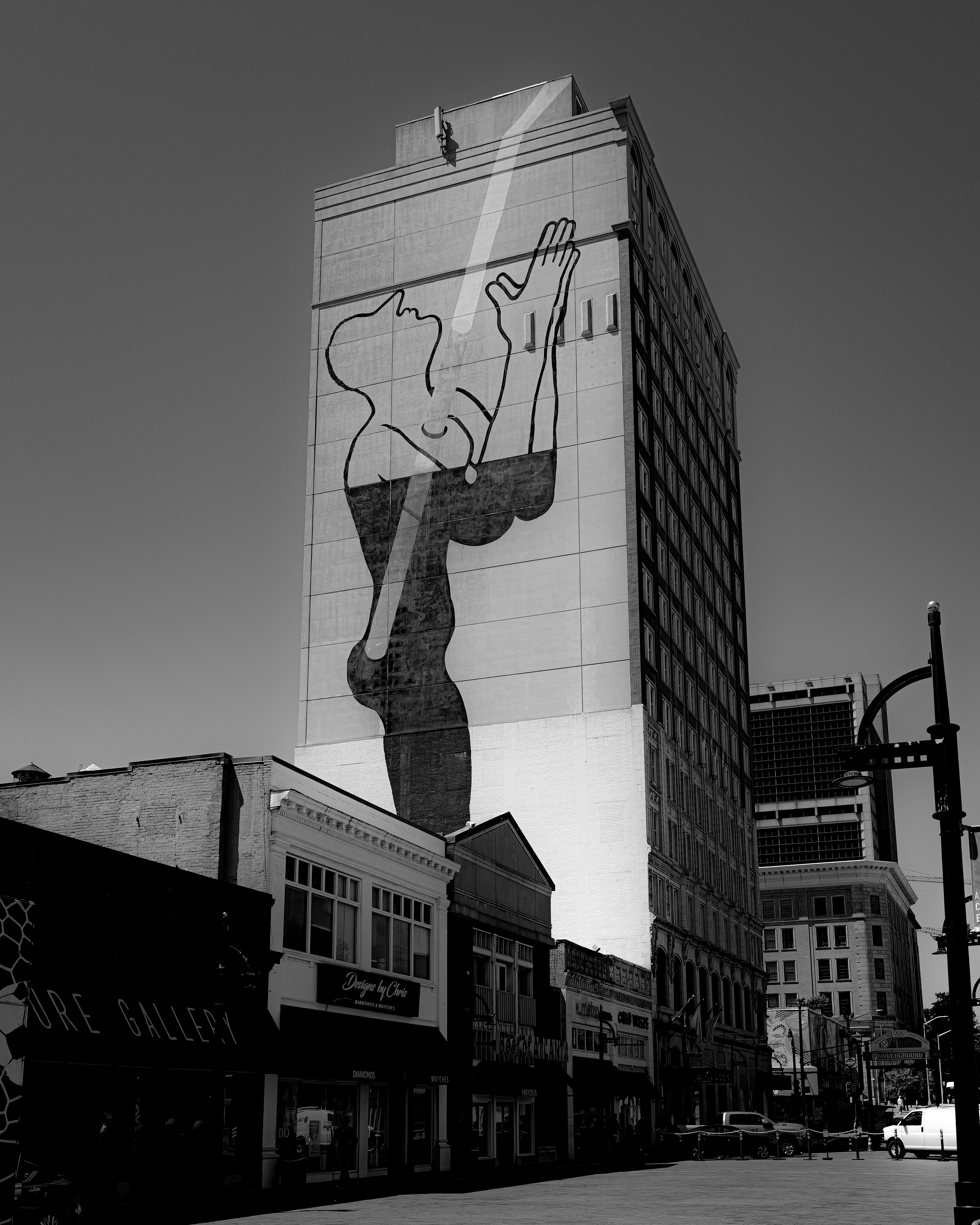 A mural adorns a tall building in black and white.