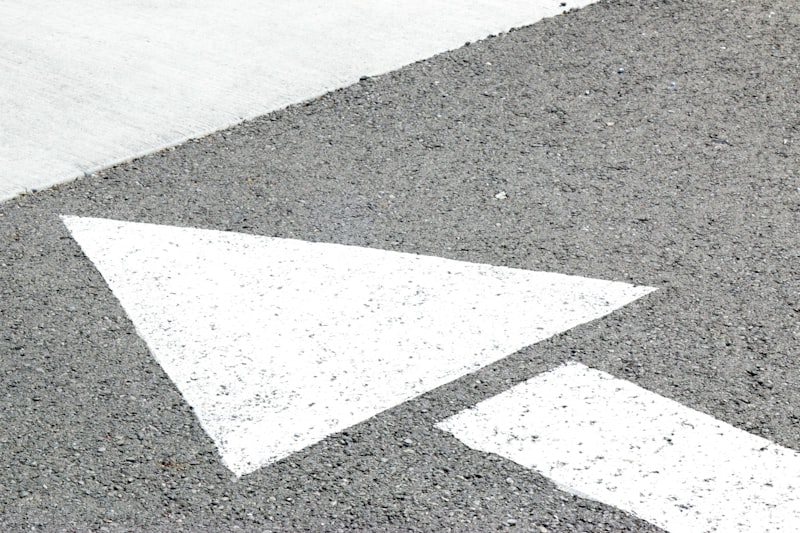 Fresh white directional arrow painted on a commercial parking lot surface