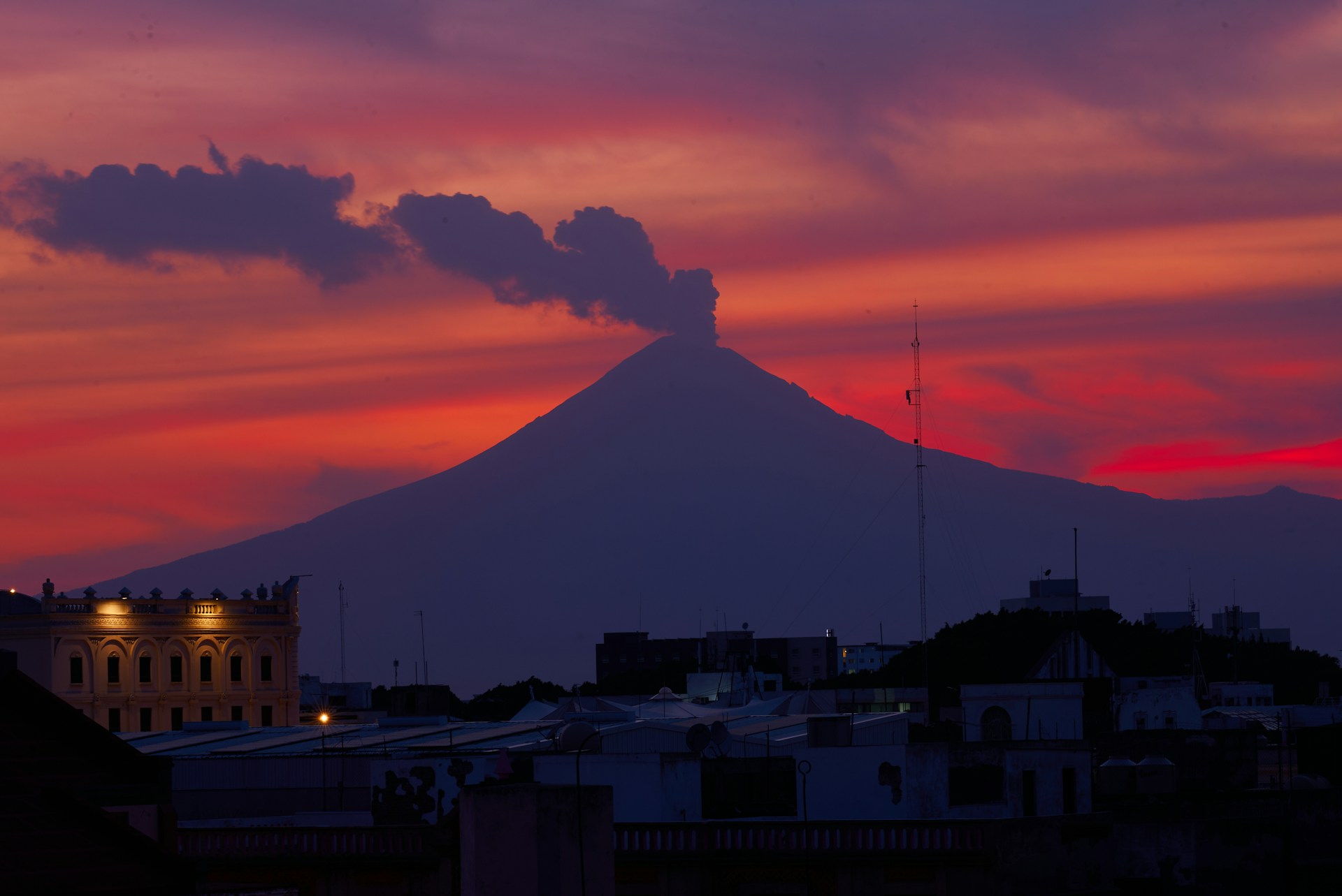 Volcano erupts against a vibrant, sunset sky.