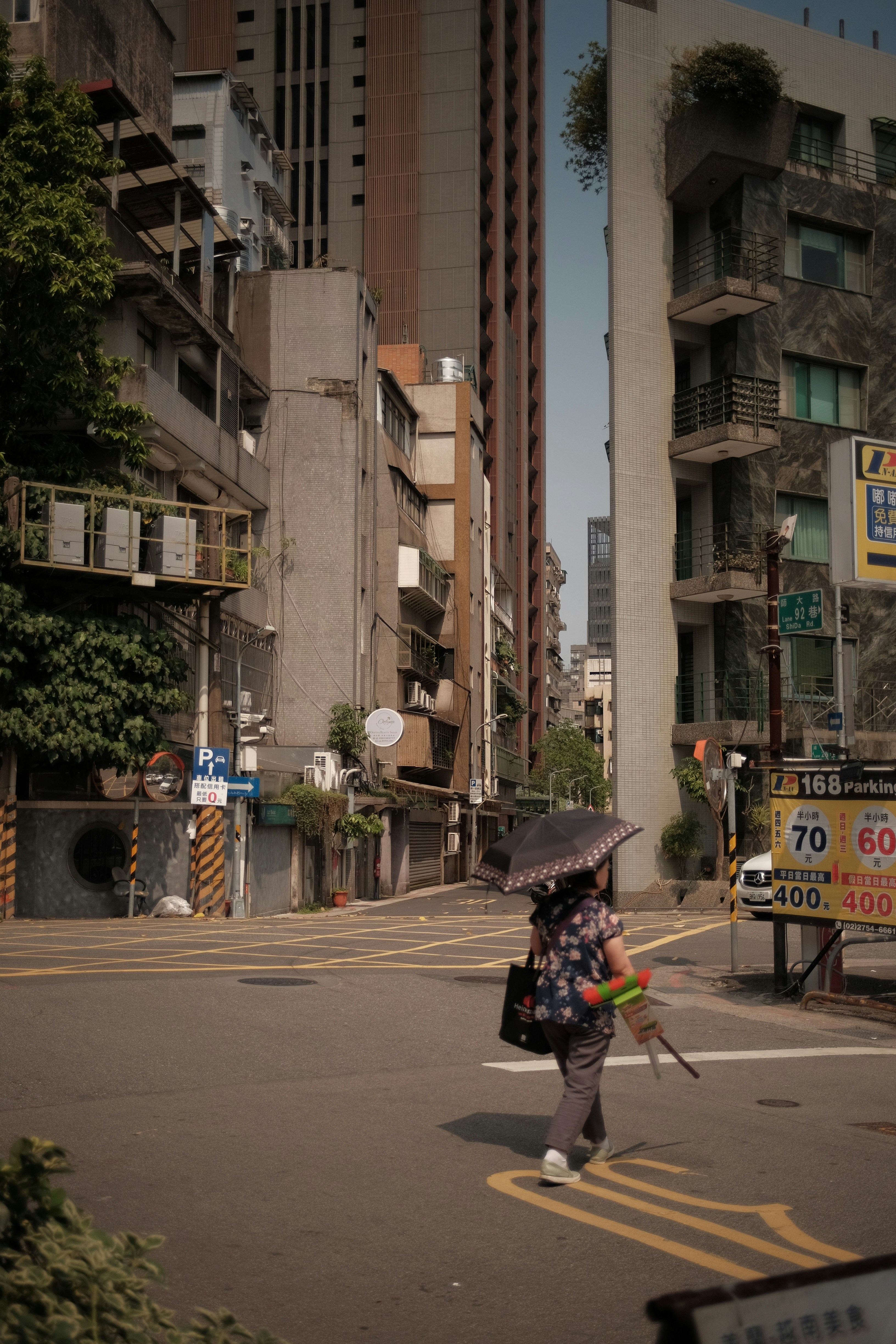 Woman with umbrella crosses a city street.
