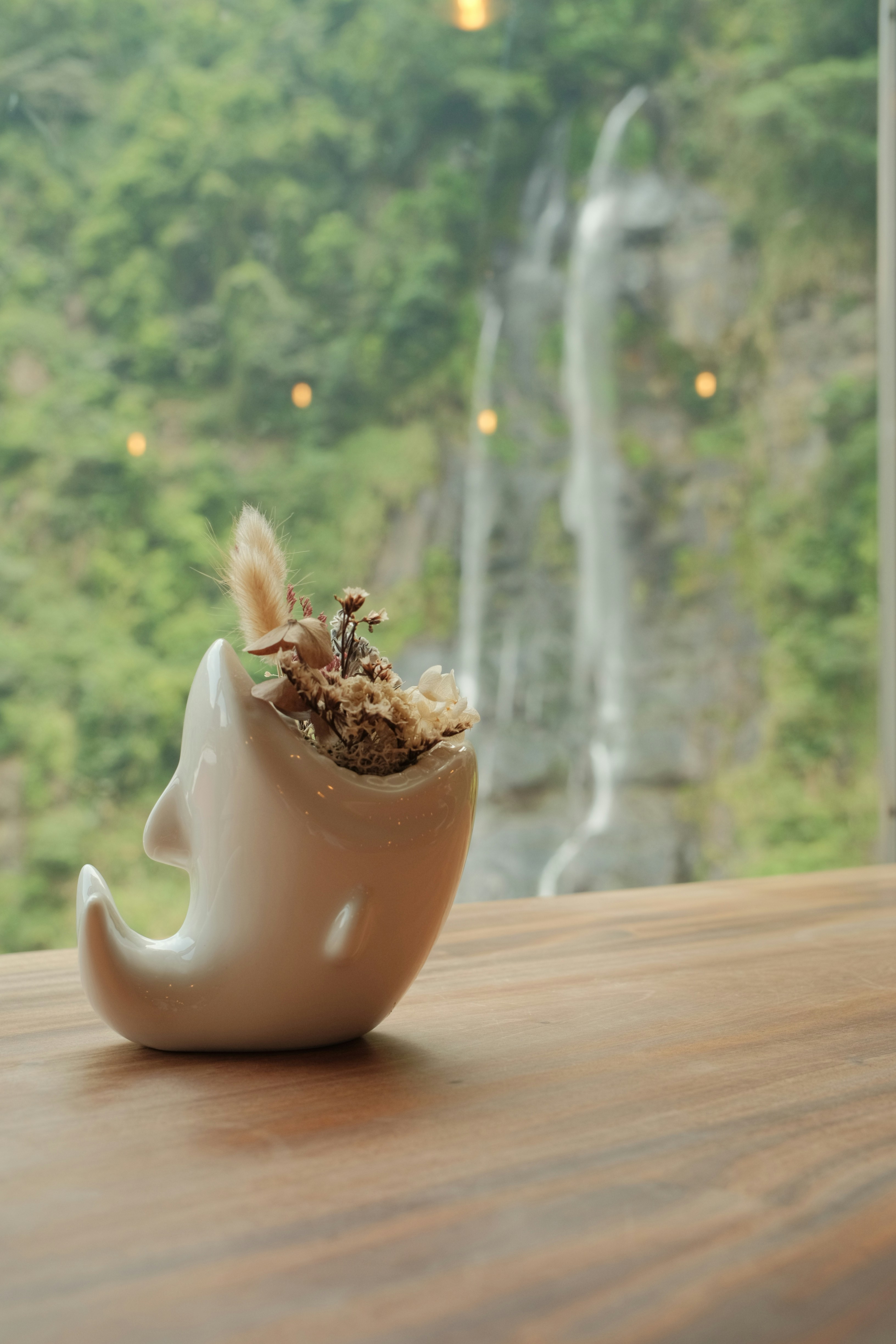 A dolphin planter sits before a waterfall view.