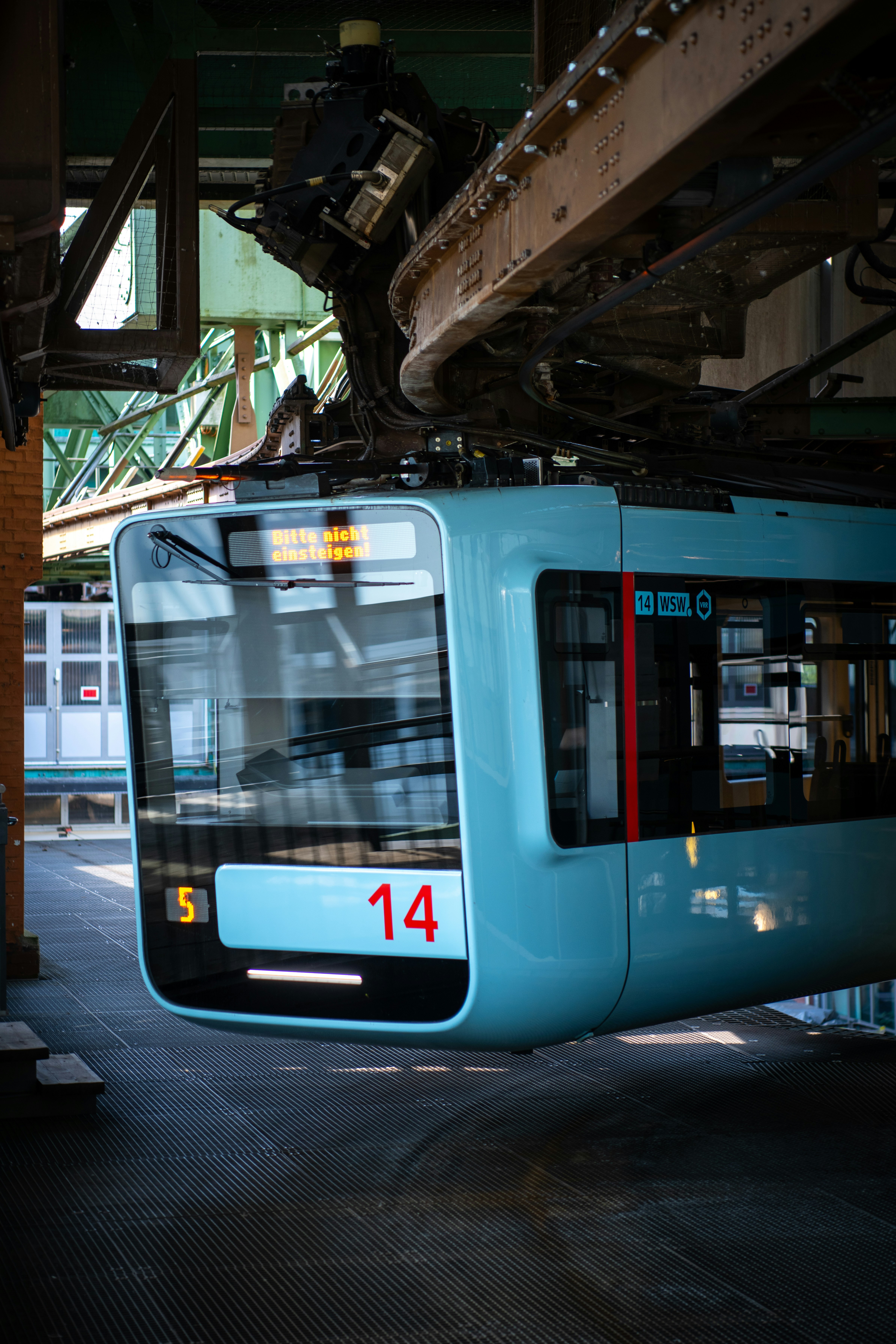 A light blue monorail train is on its track.