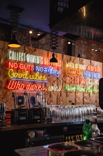 Neon signs decorate a bar's wall with motivational quotes.