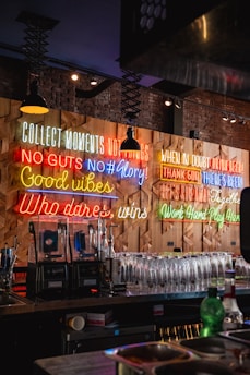 Neon signs decorate a bar's wall with motivational quotes.
