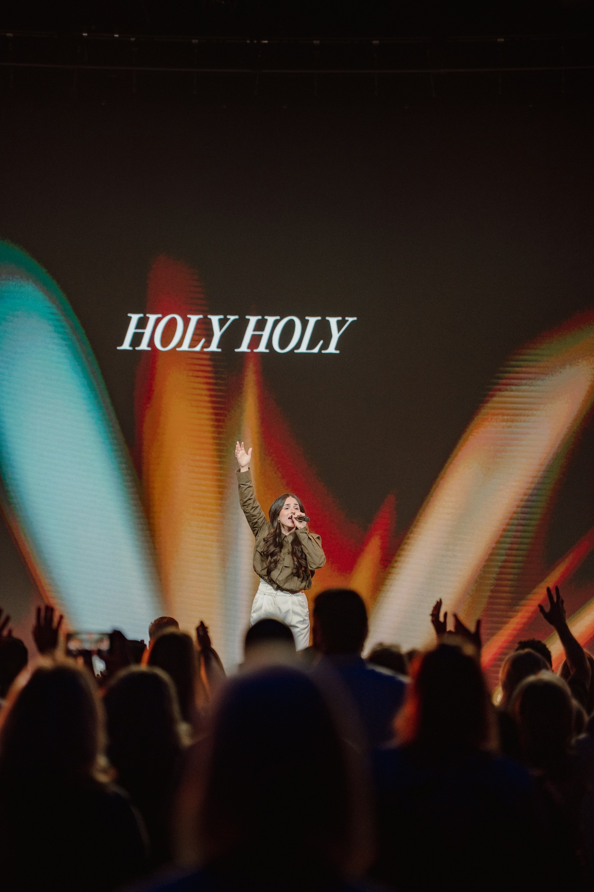 A singer leads worship, with hands raised.