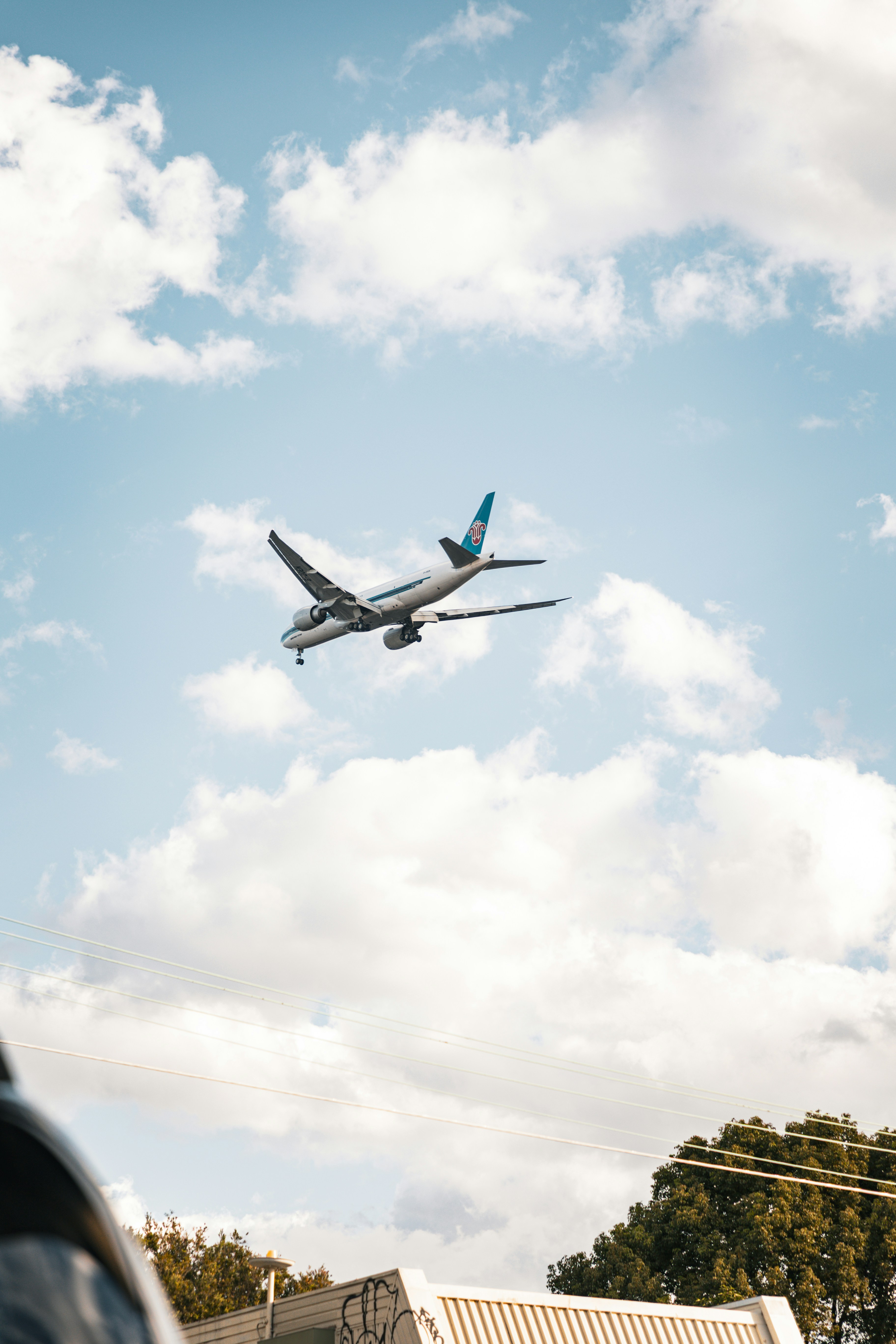 Airplane flies amidst cloudy, blue sky