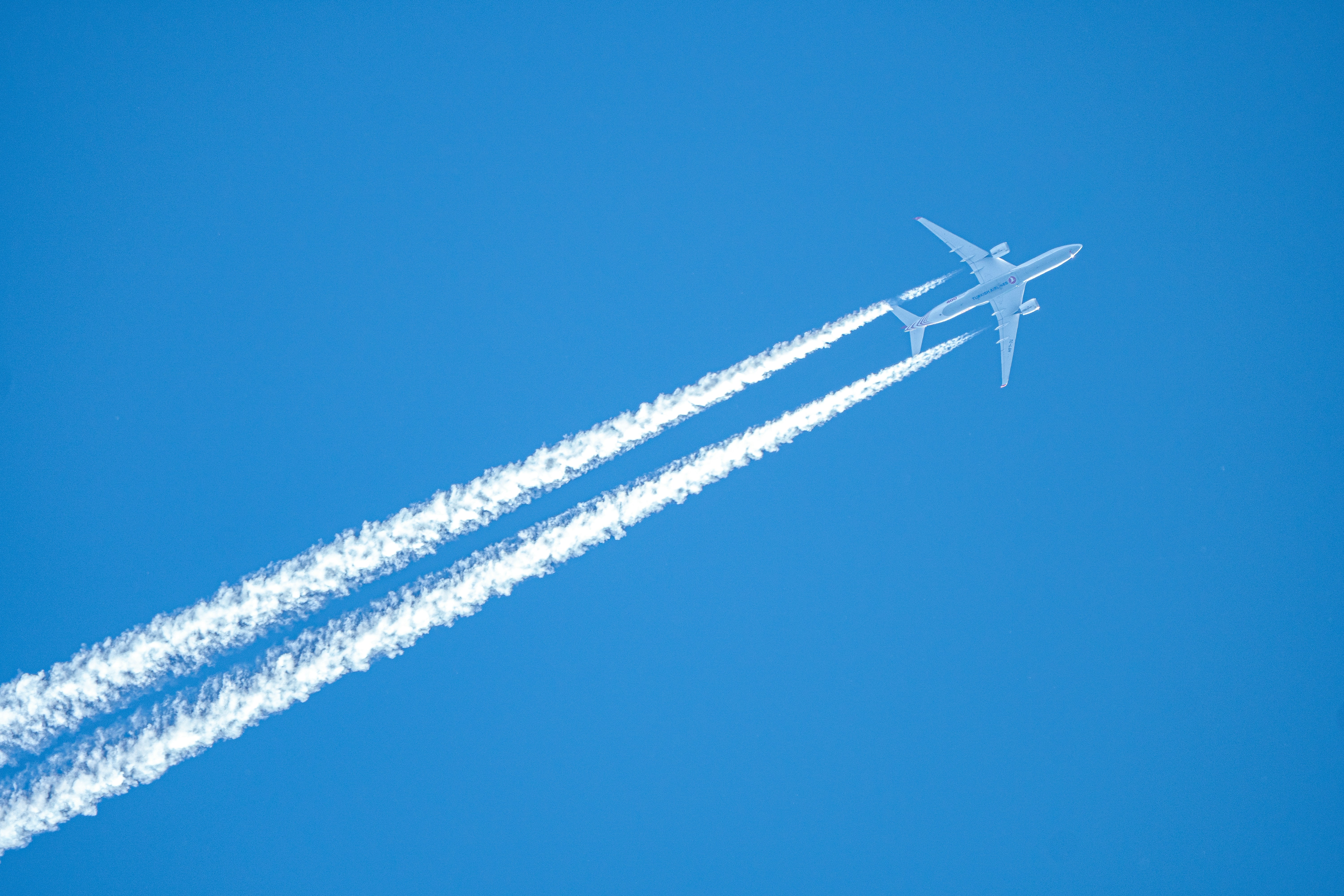 An airplane leaves contrails in a clear blue sky., 