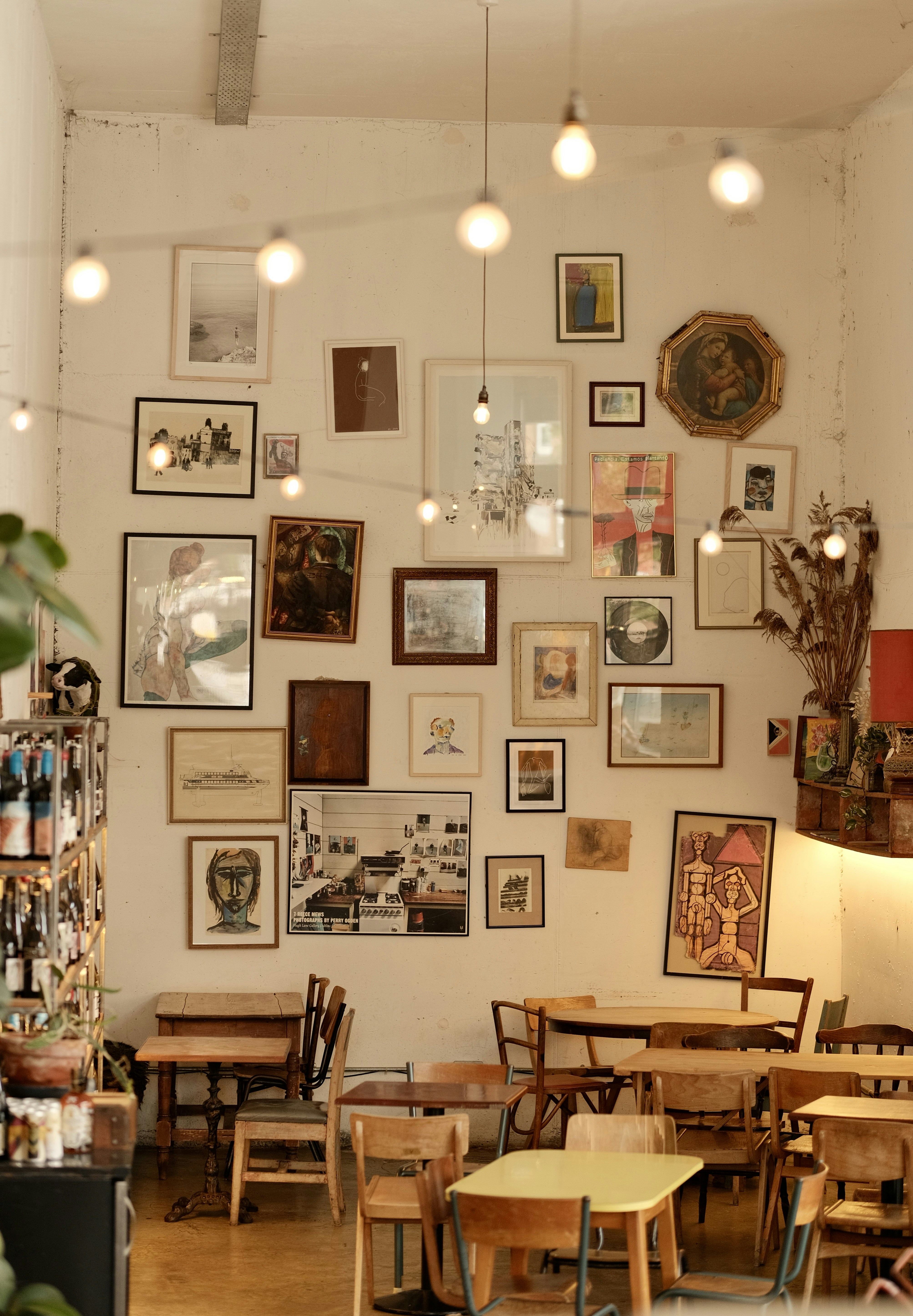 Un intérieur de café confortable avec des œuvres d’art et des lumières suspendues.