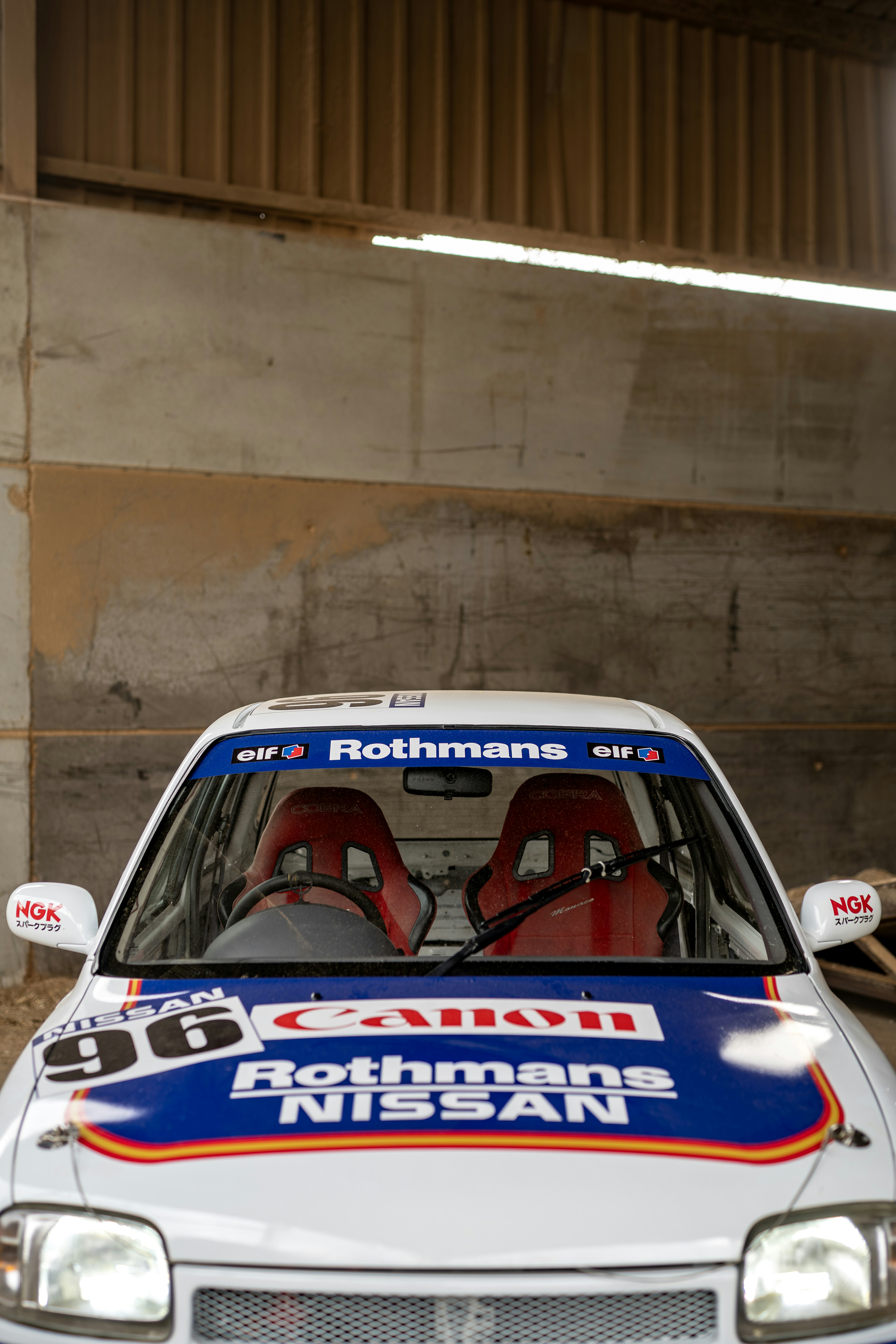 A nissan race car is parked in a garage.