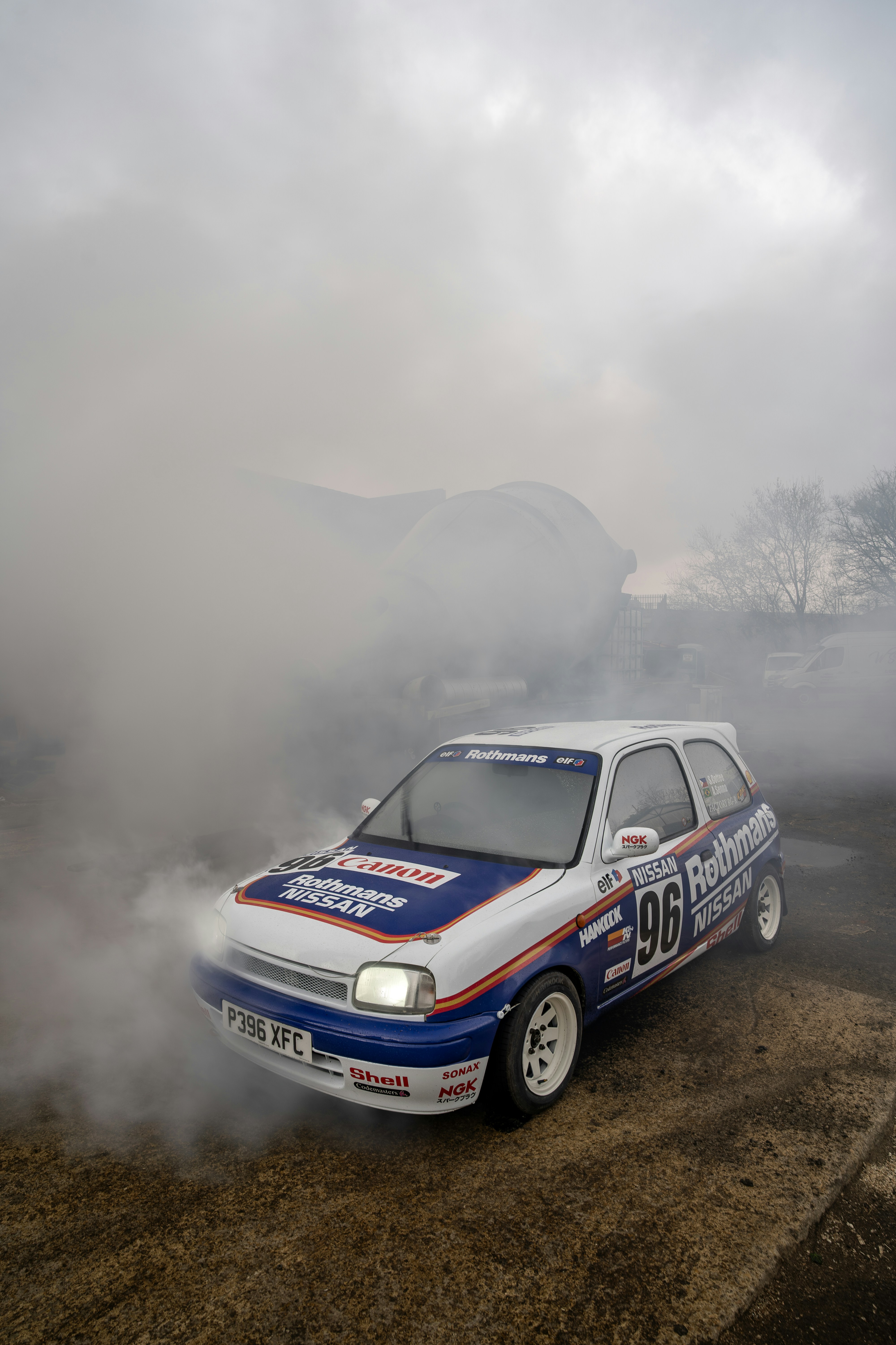 A rally car performs a smoky burnout.