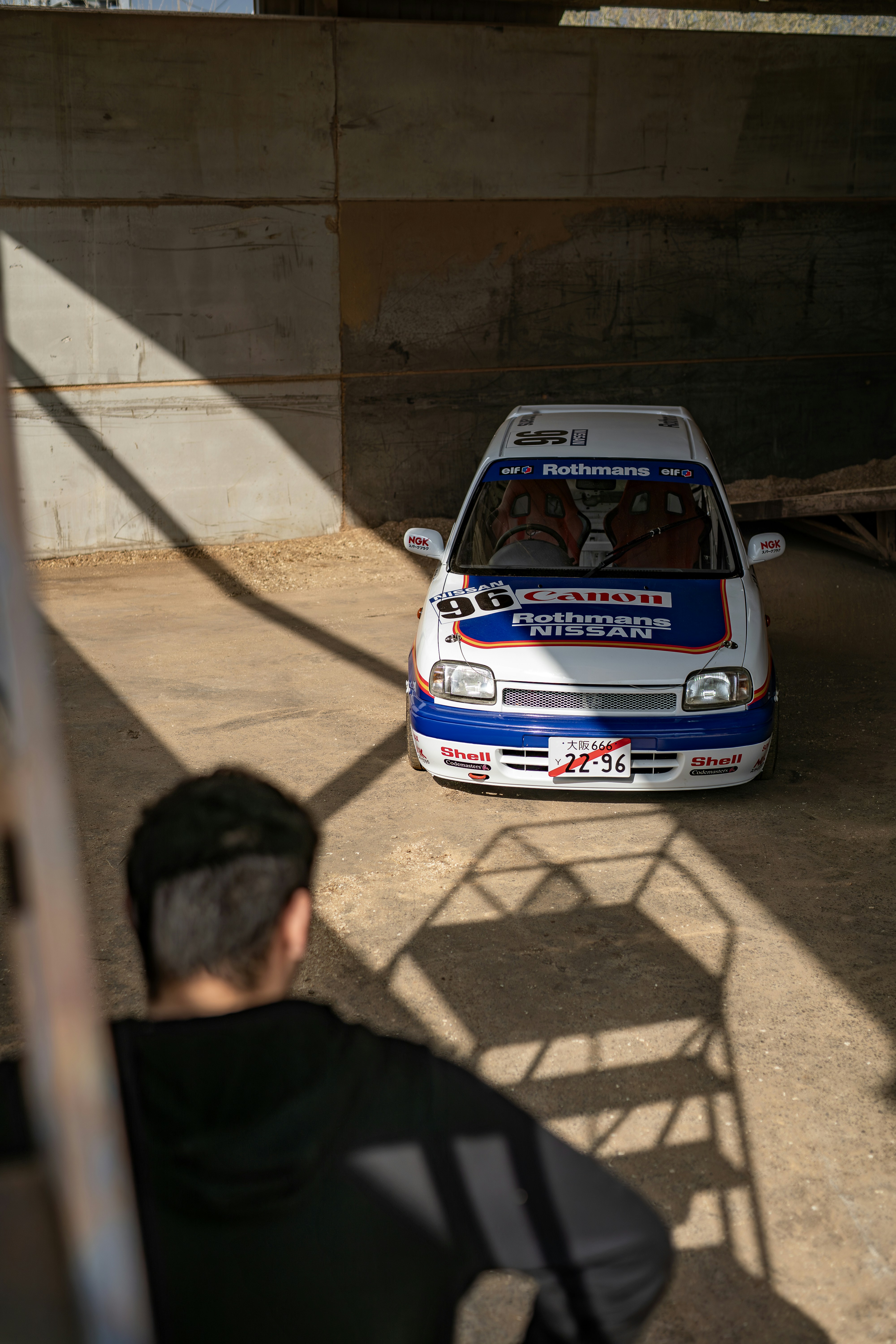 Man admires a white car in a garage.
