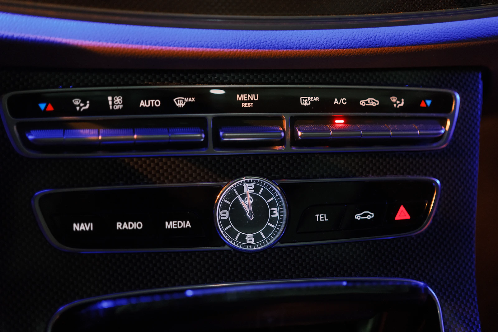 Glowing blue car climate-control panel with the A/C button lit on a dashboard