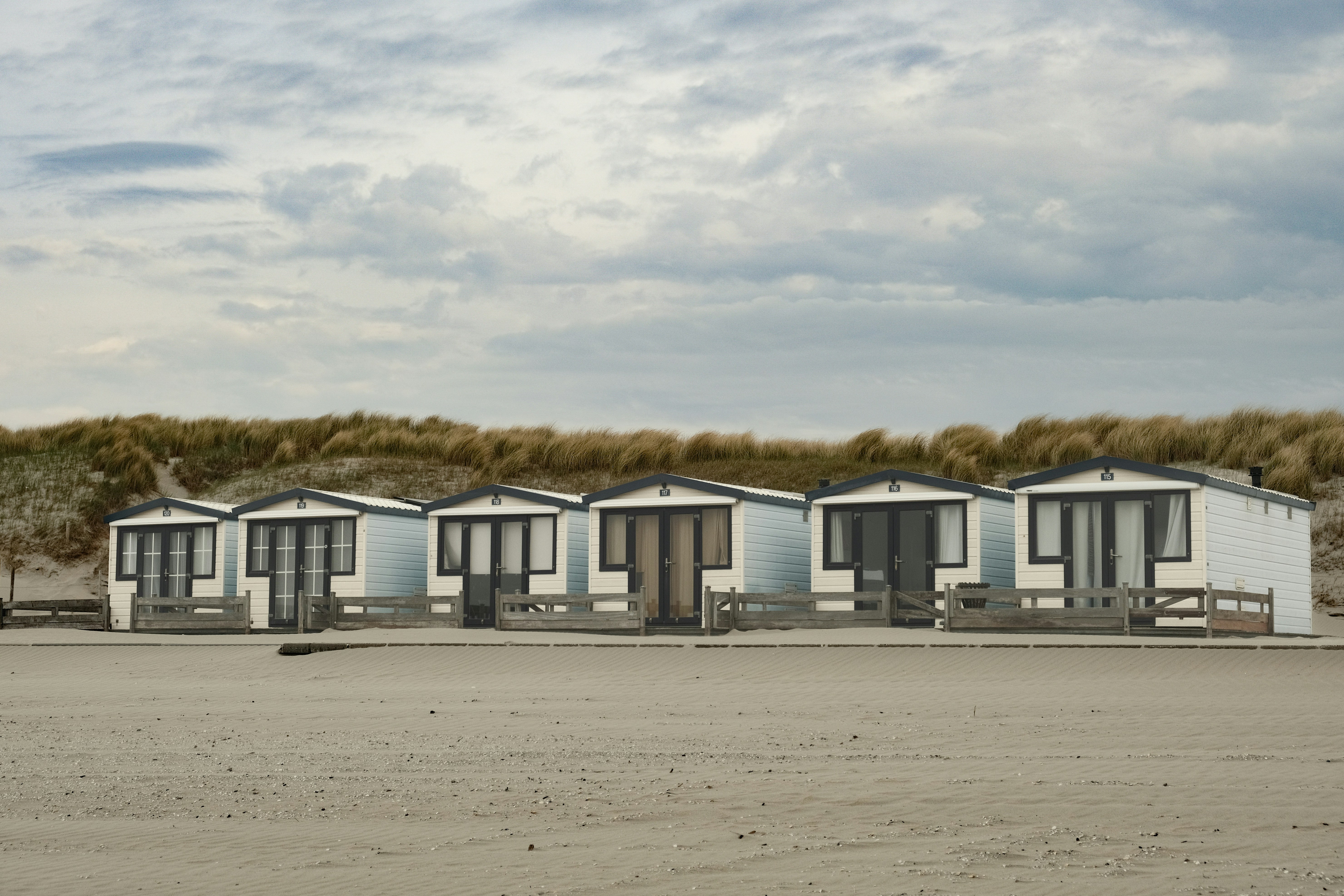 Beach huts are lined up on the sandy beach.