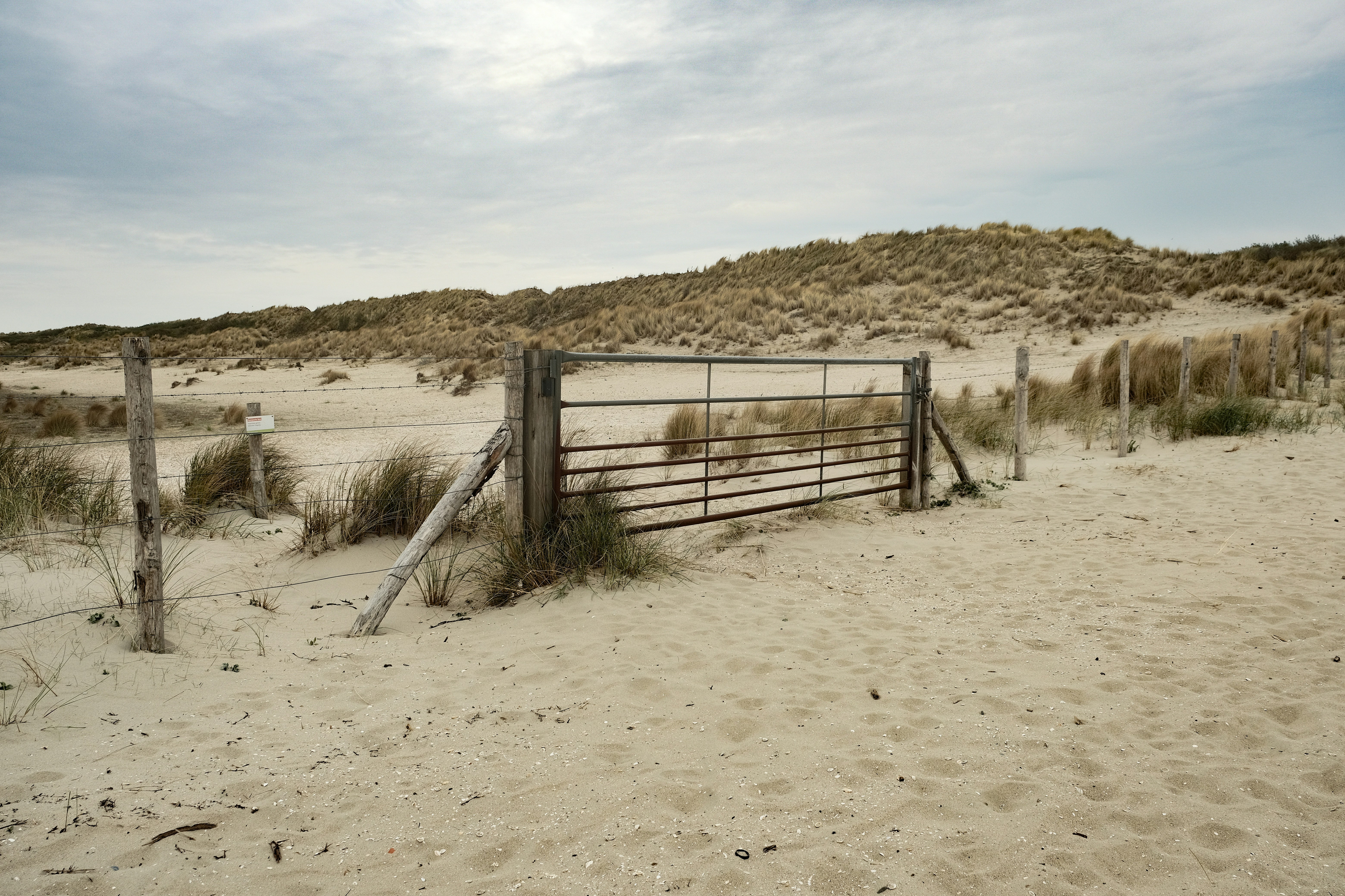 A gate leads to sandy dunes.