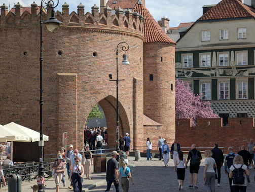 People walk through a historic brick archway.
