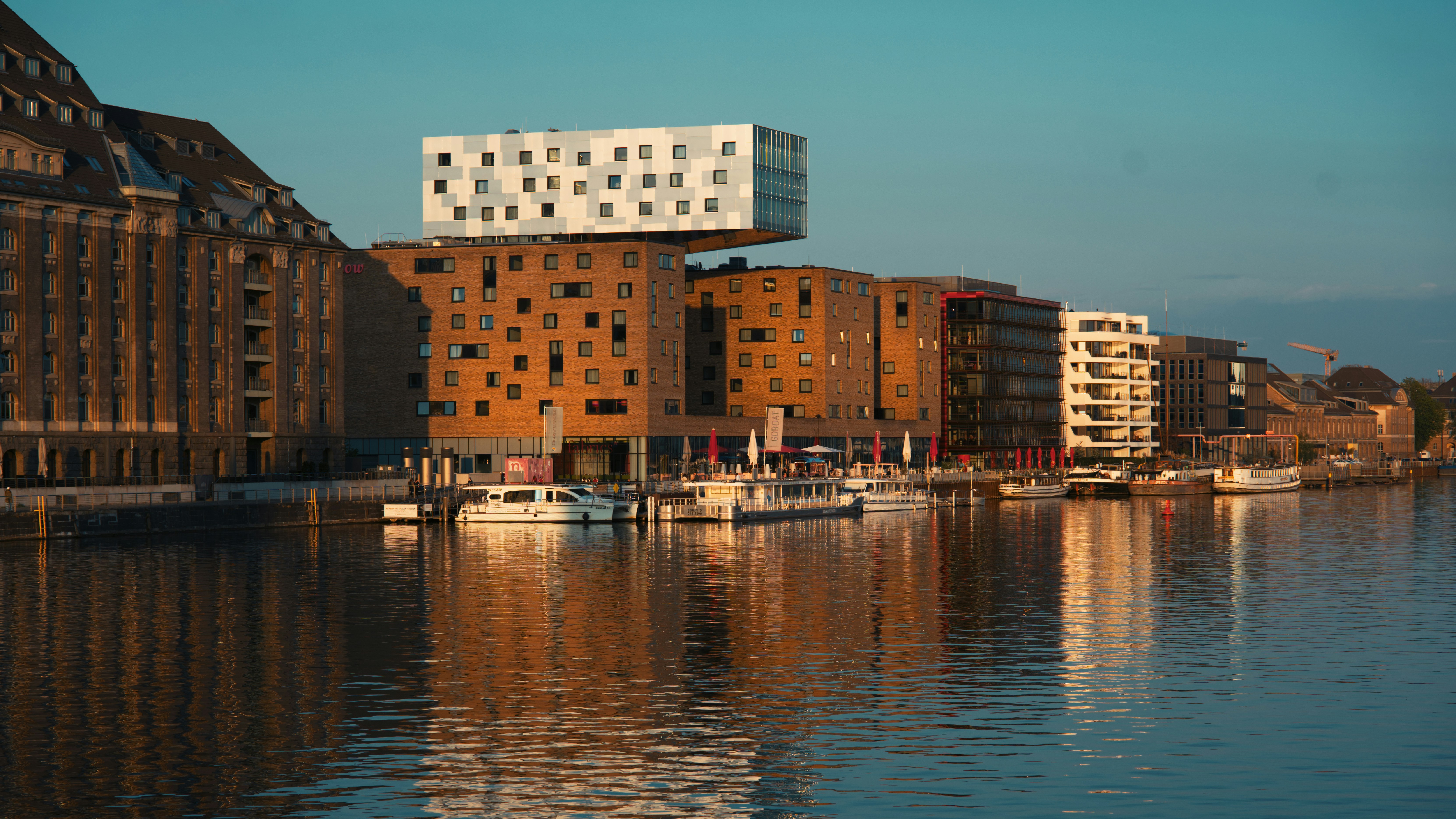 Buildings line a river with boats in the water.