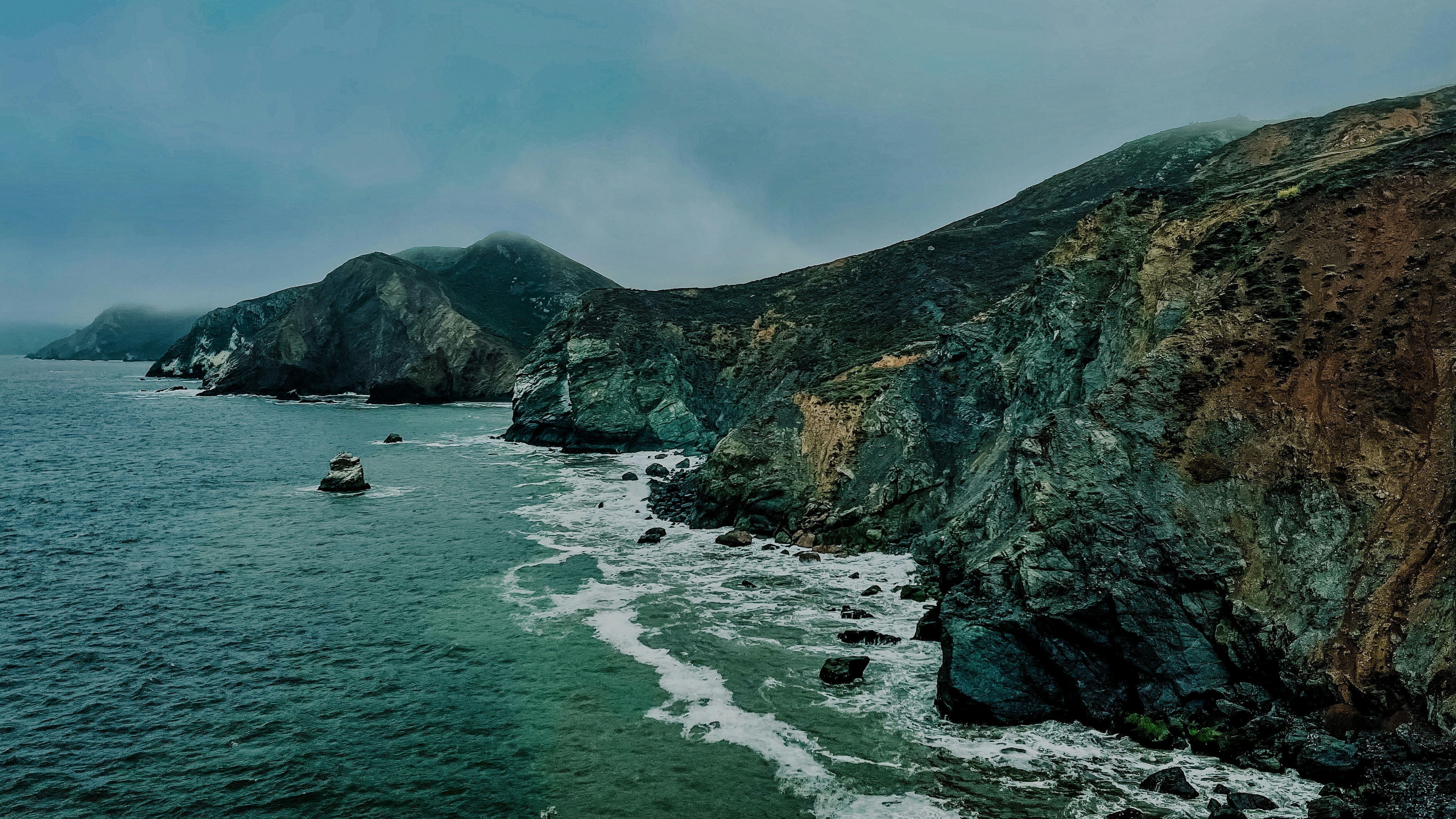 Zerklüftete Küste mit einem Boot im Meer.