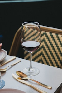 A wine glass and cutlery sit on a table.