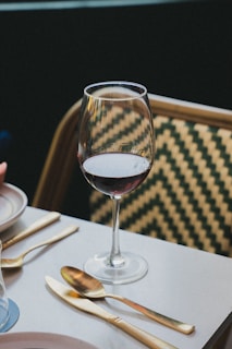 A wine glass and cutlery sit on a table.