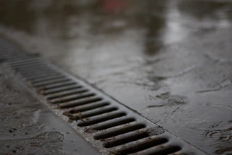 A metal drain on a wet concrete surface.