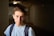 Young man stands in a dark corridor.