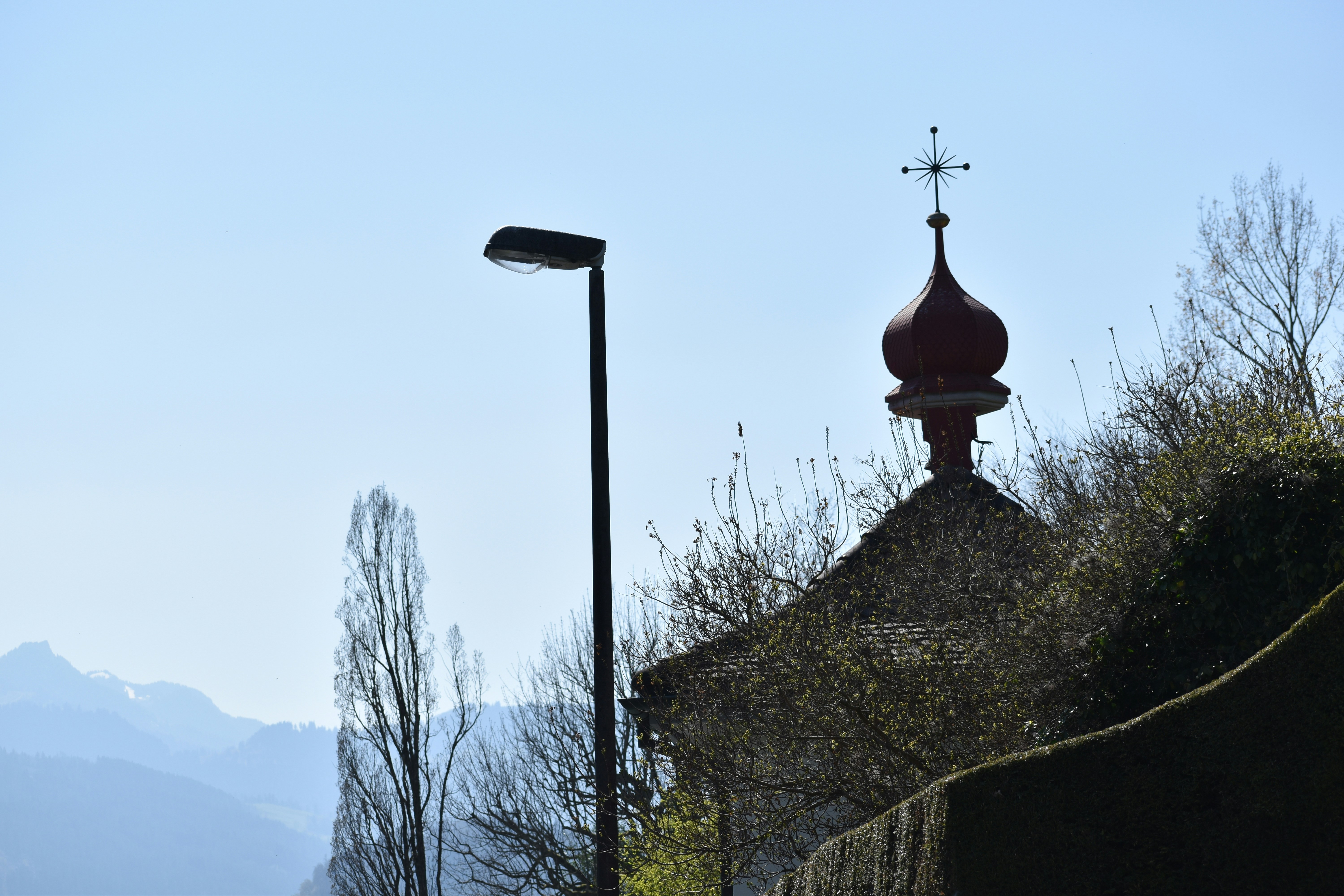 A chapel and lamppost silhouetted against a blue sky.