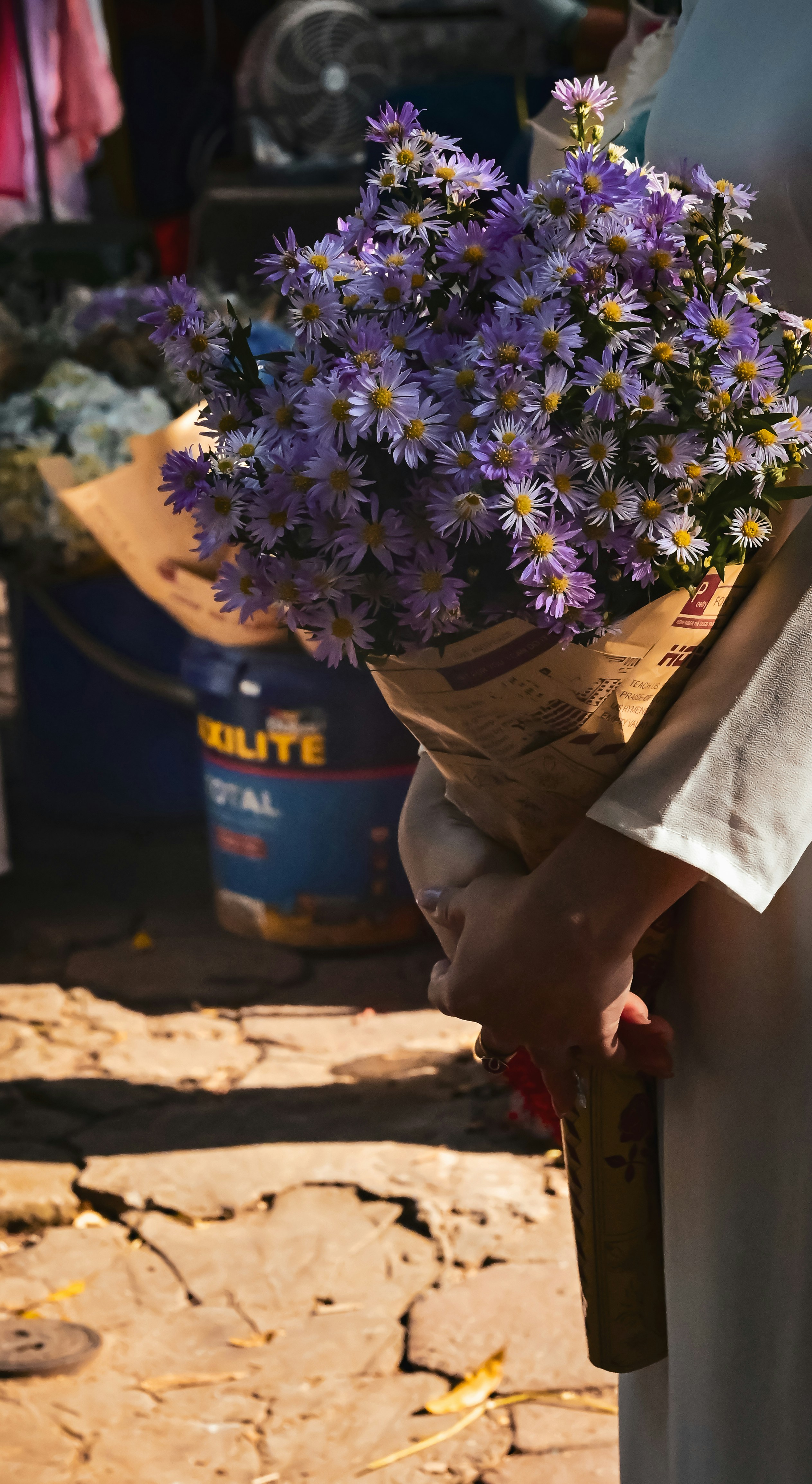 A person holds a bouquet of purple flowers.