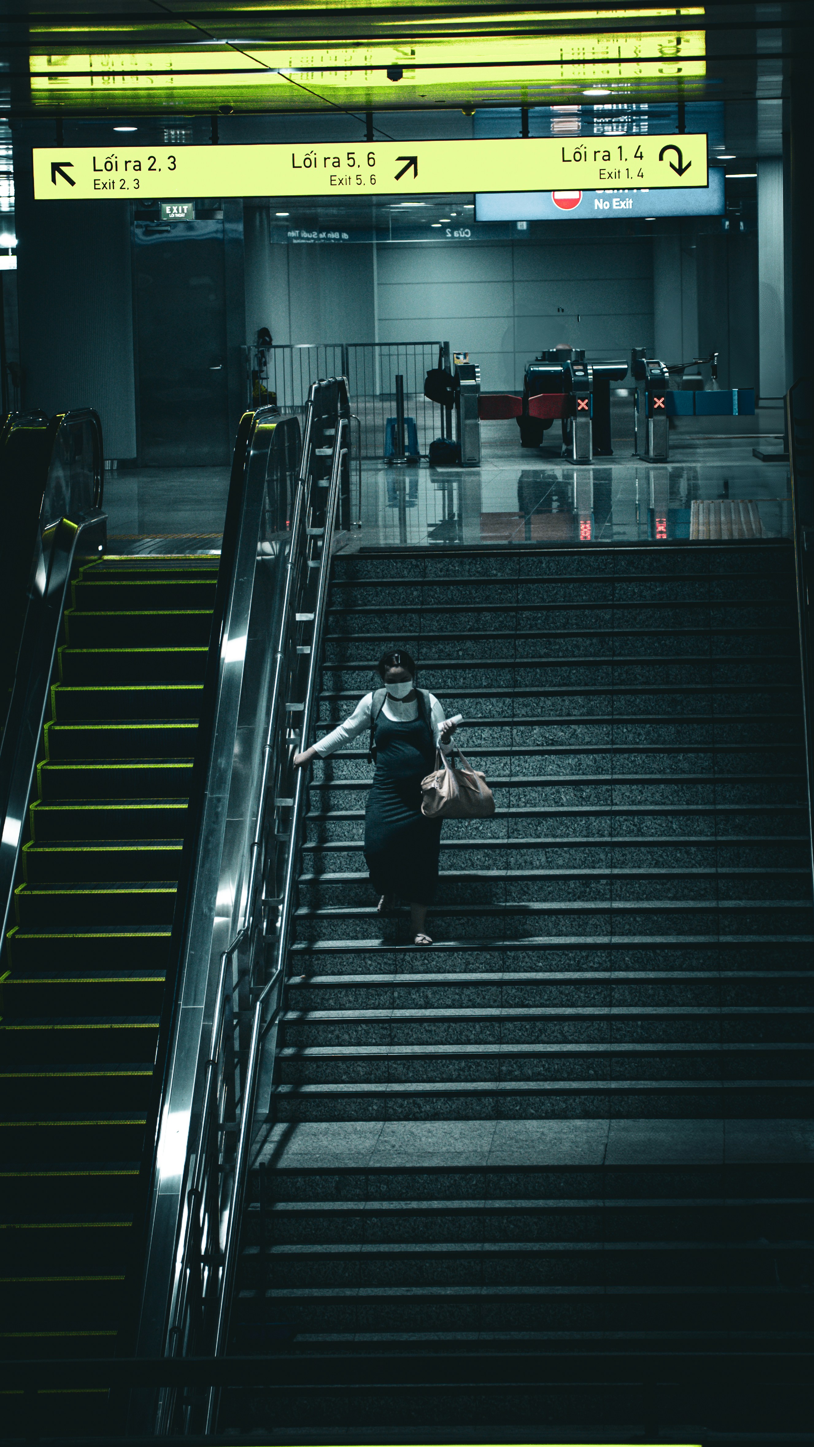 A woman descends stairs in a subway station.