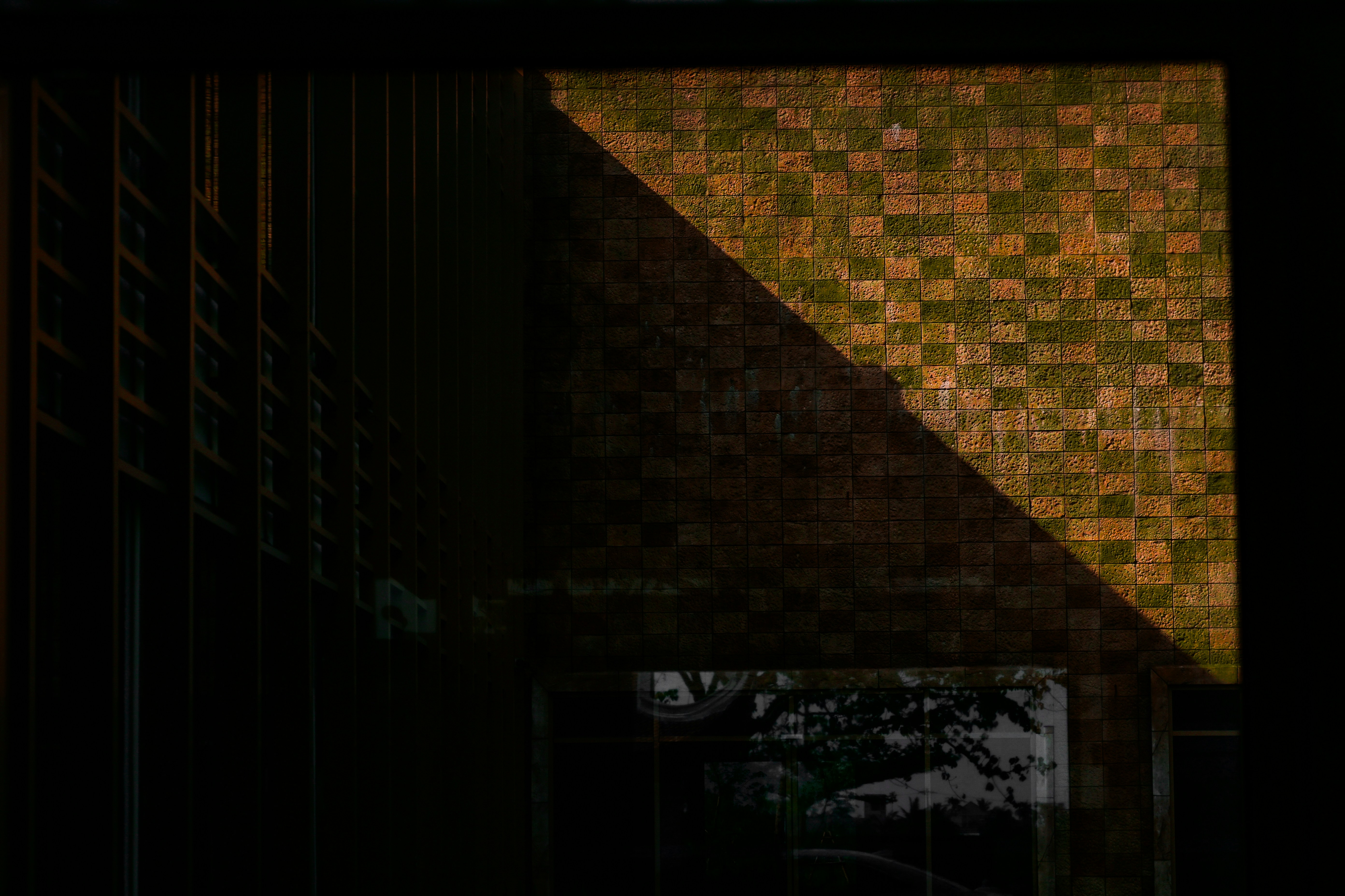 A tile wall with a diagonal, illuminated by light.