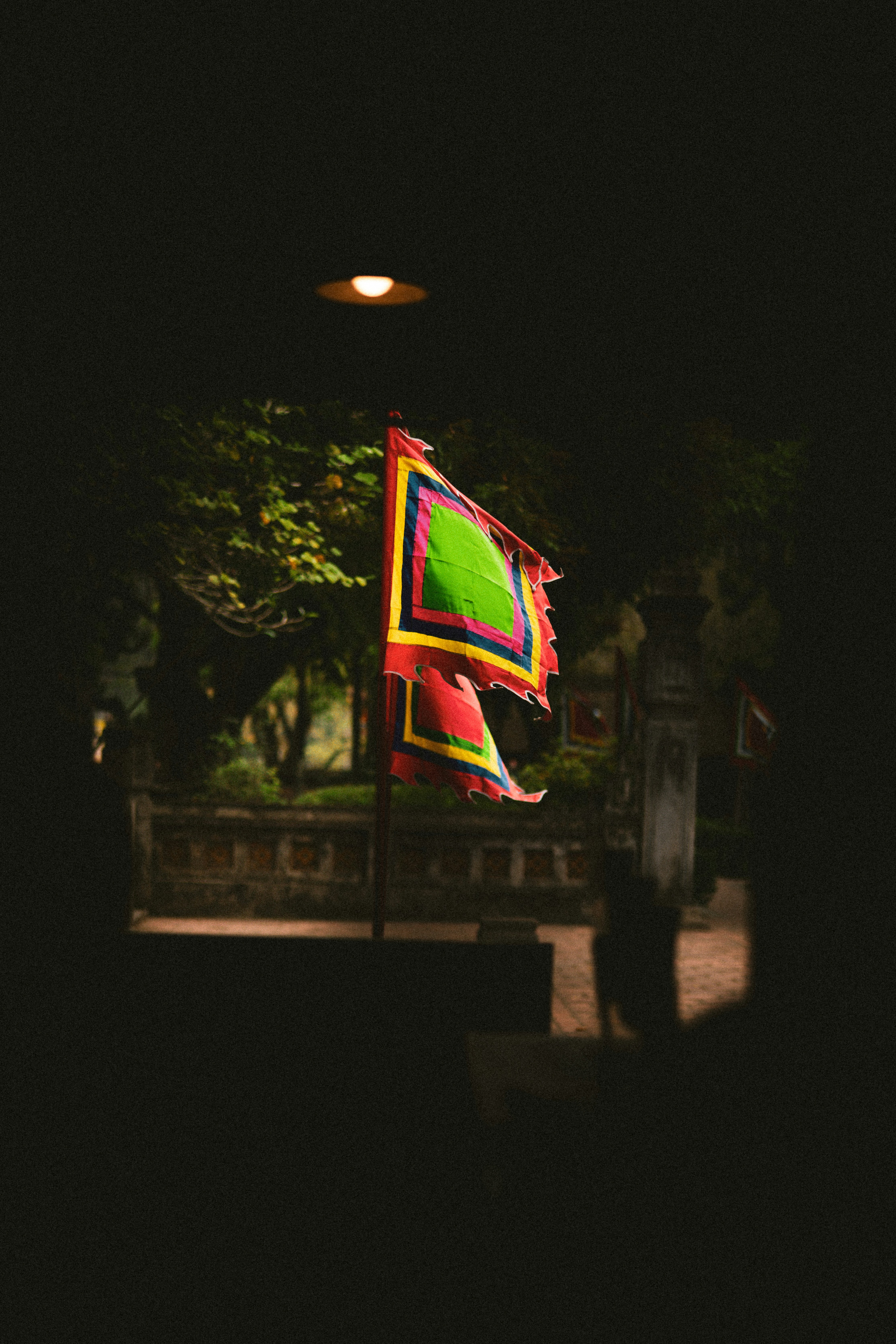 A colorful flag flutters outdoors in dim light.