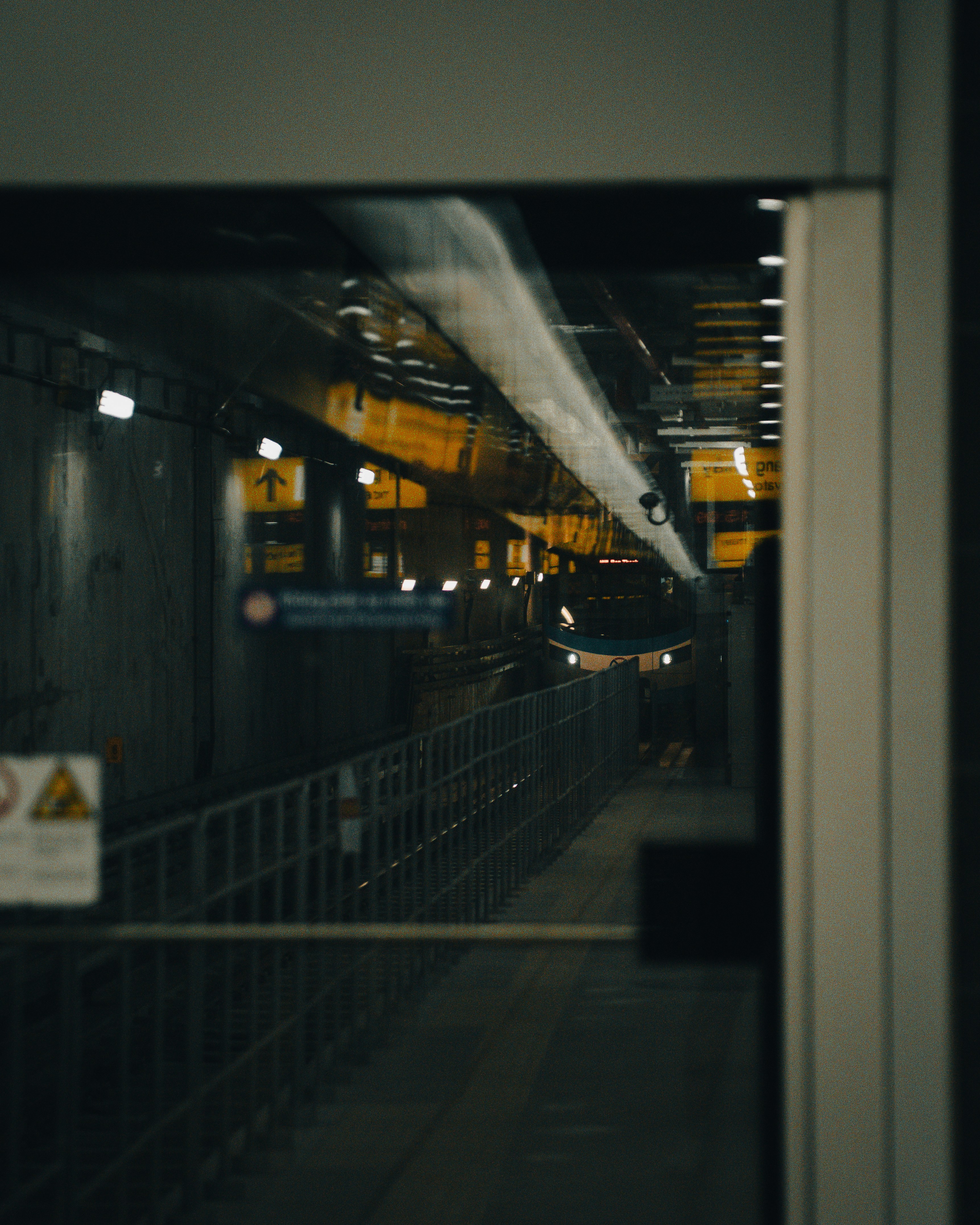 A train approaches a dark, empty subway station.