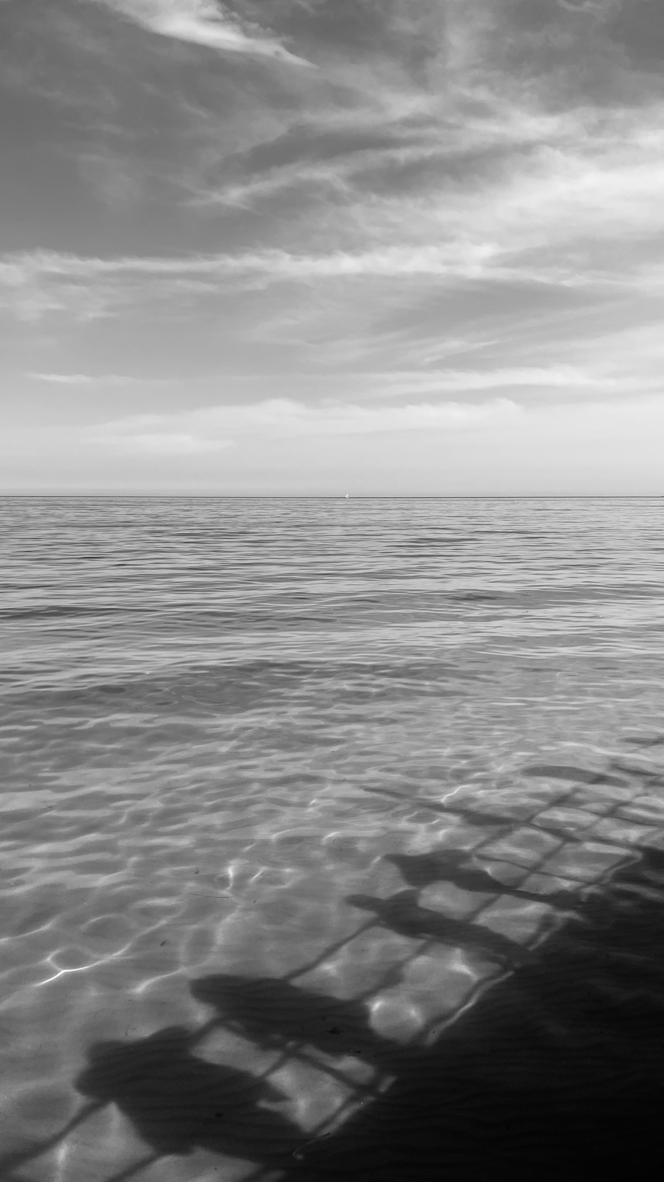 Shadows cast onto the water under a cloudy sky.