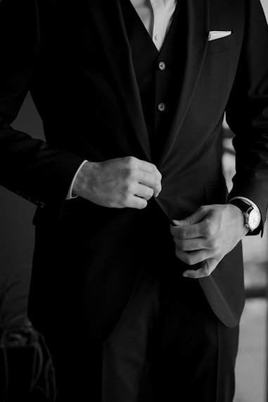 A man is adjusting his formal suit.