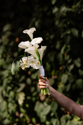 A hand holds a beautiful bouquet of white flowers.