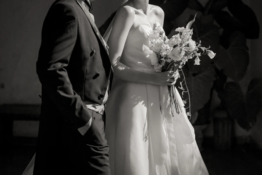 Bride with bouquet and groom in a tailcoat side by side, black and white