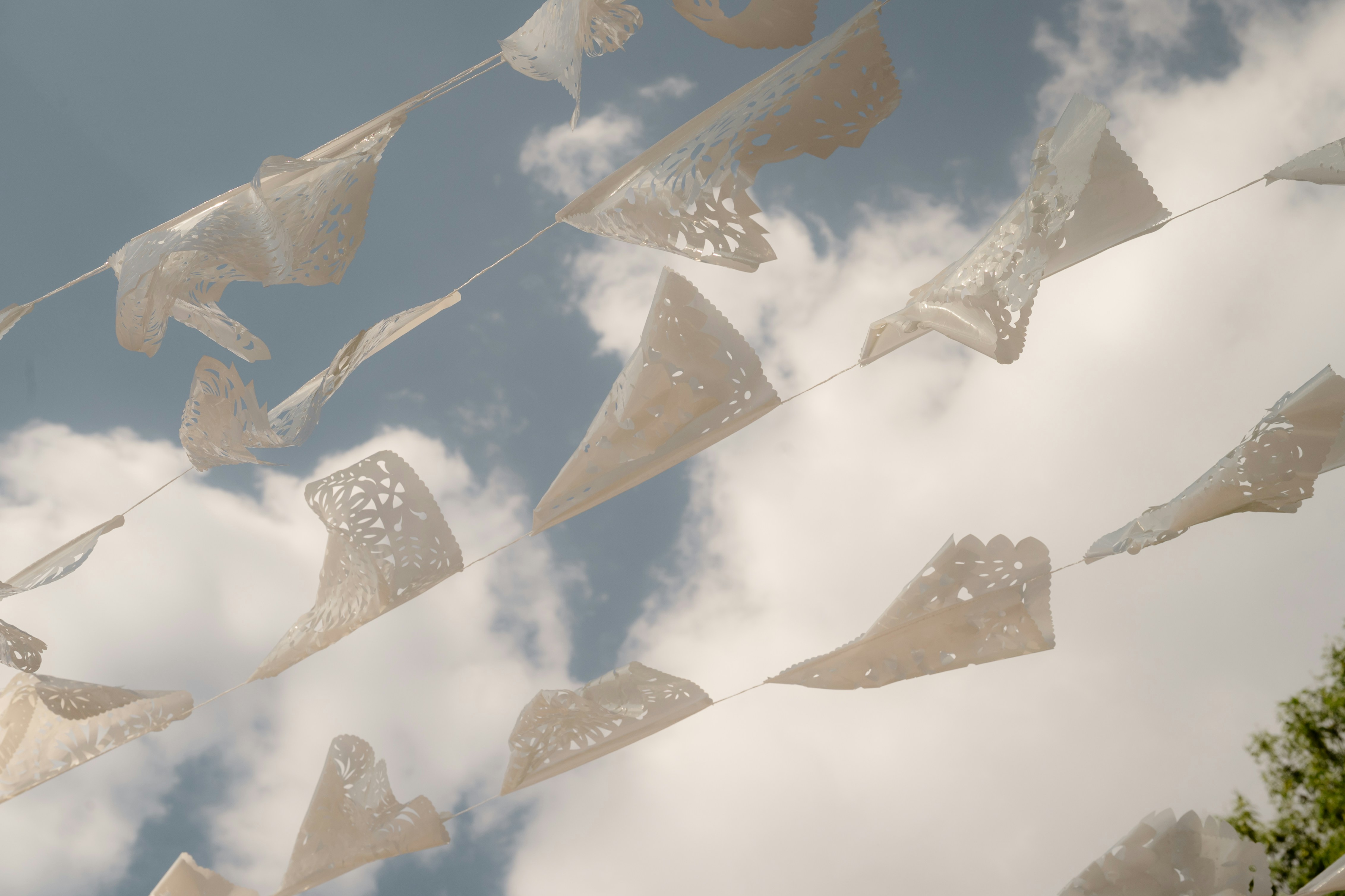 Flags are hanging against a cloudy, blue sky.