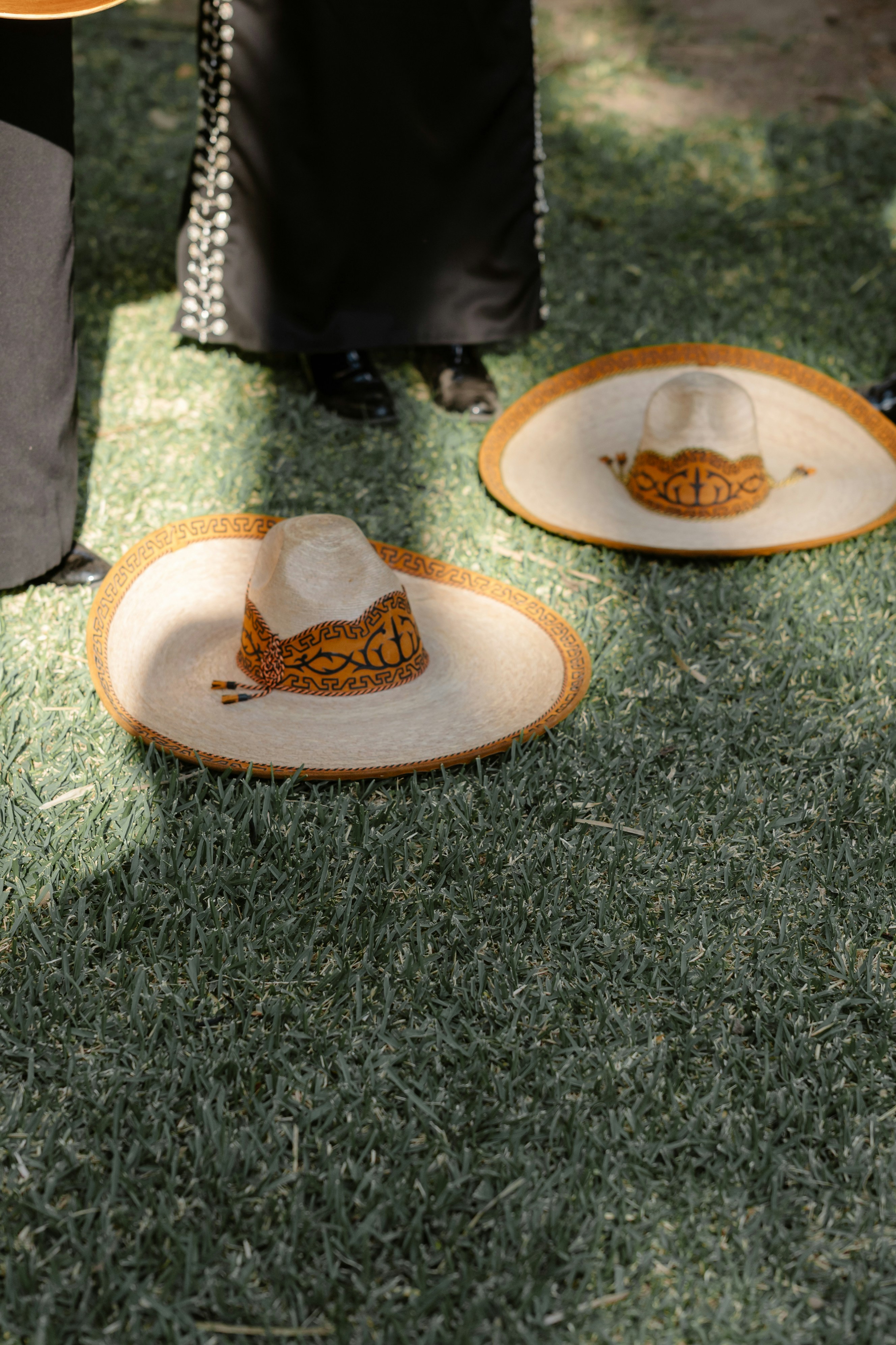 Two sombreros rest on the green grass.