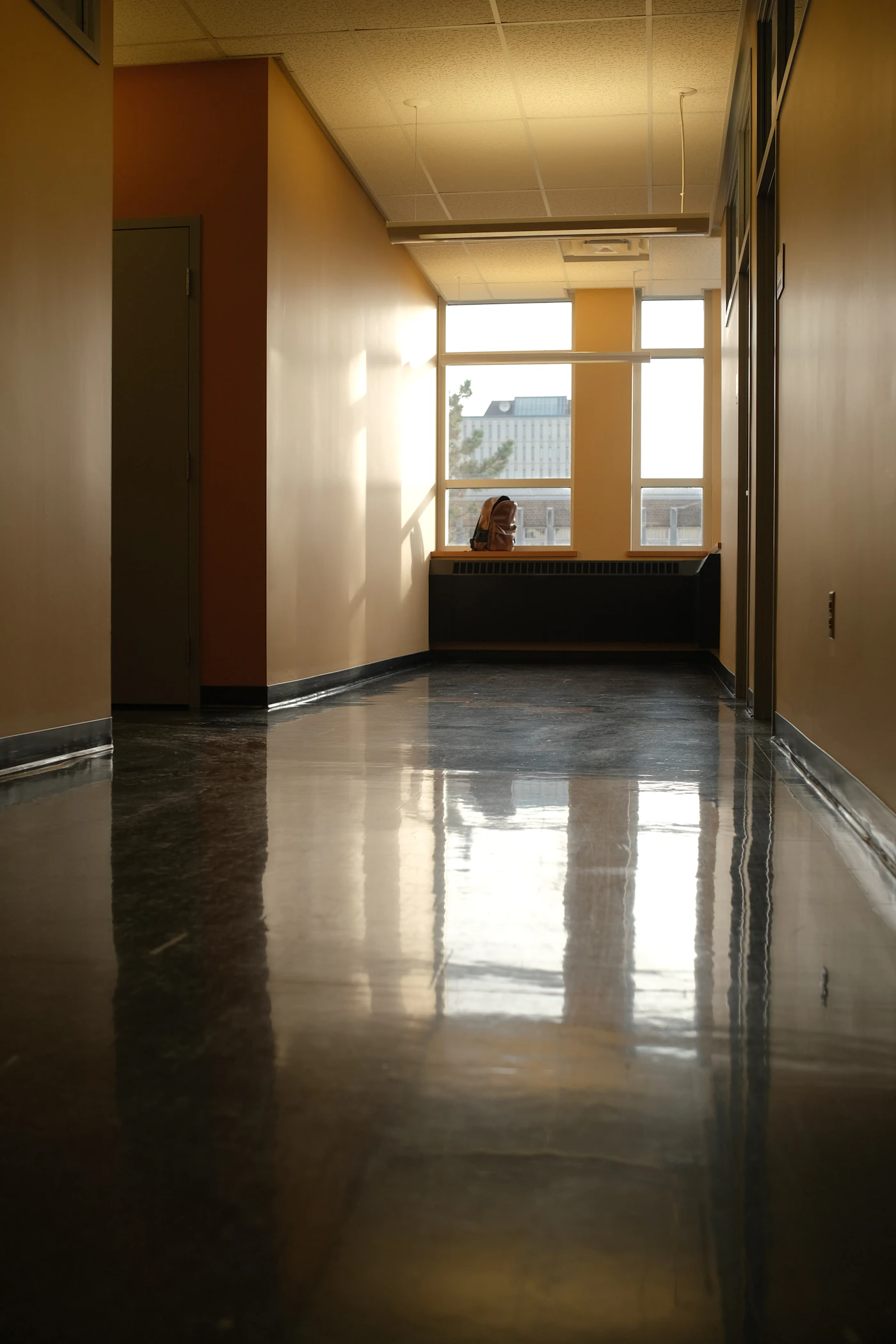 A long hallway with a mirror-gloss floor reflecting the sunlight from the windows